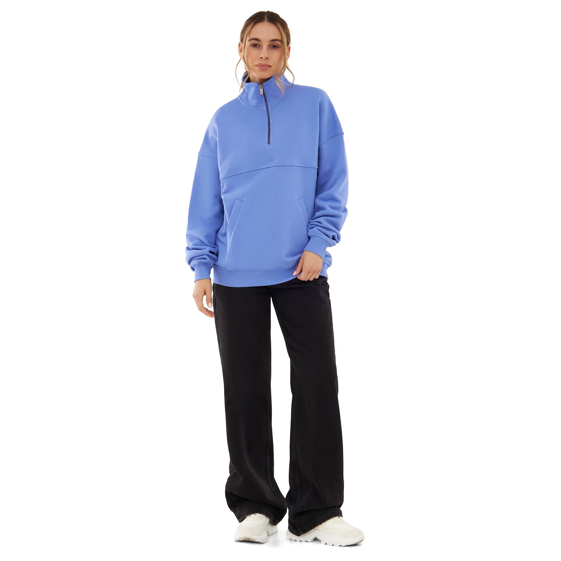 Frau trägt blauen Half-Zip-Pullover 'Cooper' von Johnny Urban mit schwarzer Hose und weißen Schuhen
