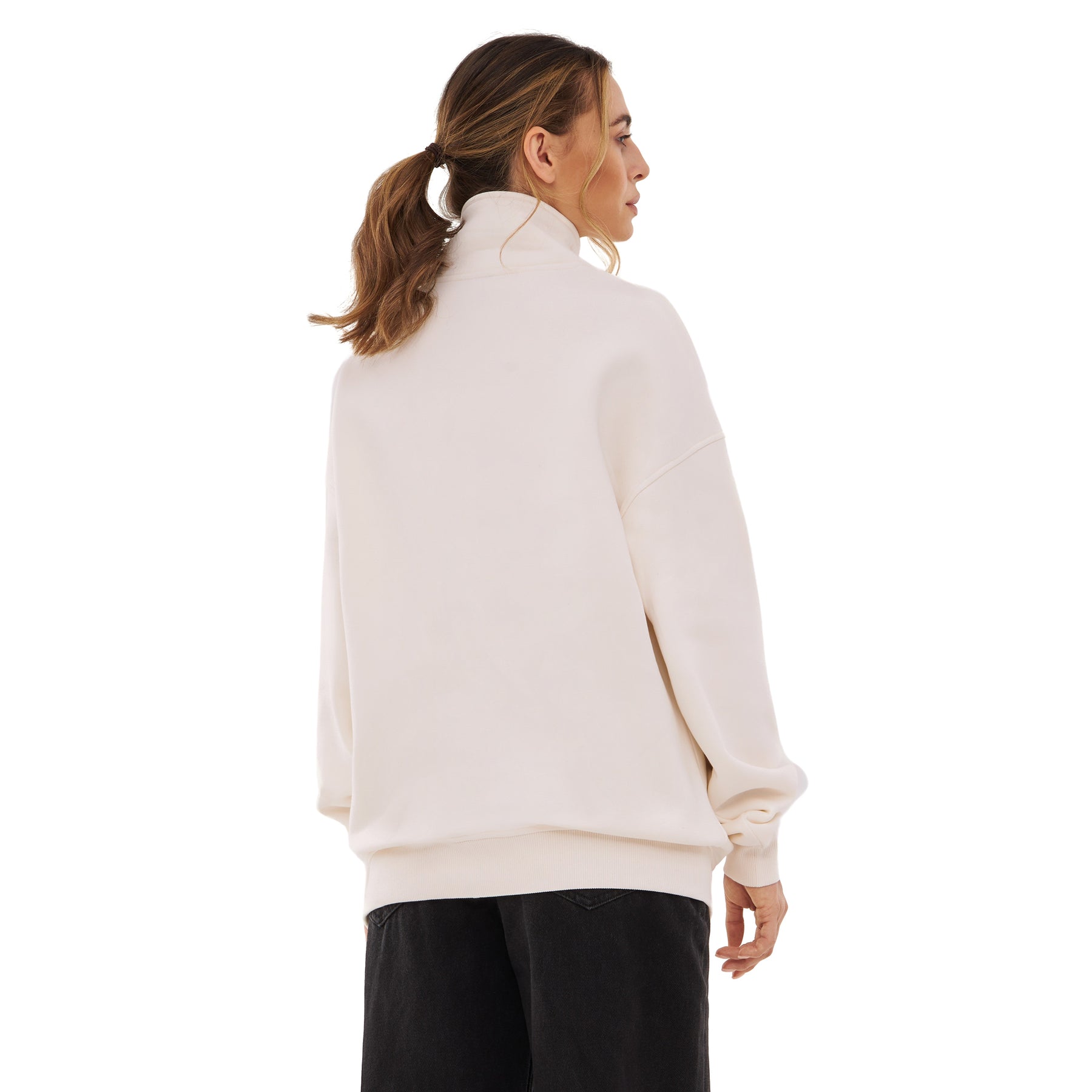 Frau von hinten in cremeweißem Half-Zip-Sweatshirt ‚Cooper‘ mit hohem Kragen und schwarzen Hosen