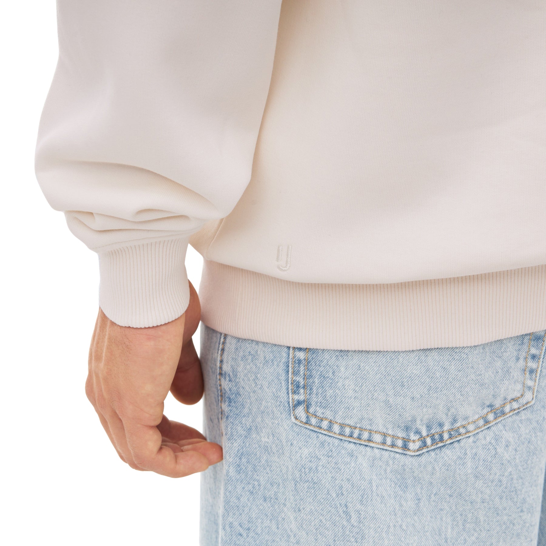 Nahaufnahme eines cremeweißen Half Zip Sweatshirts 'Cooper' mit elastischem Bündchen am Handgelenk und Saum, getragen zu hellblauen Jeans