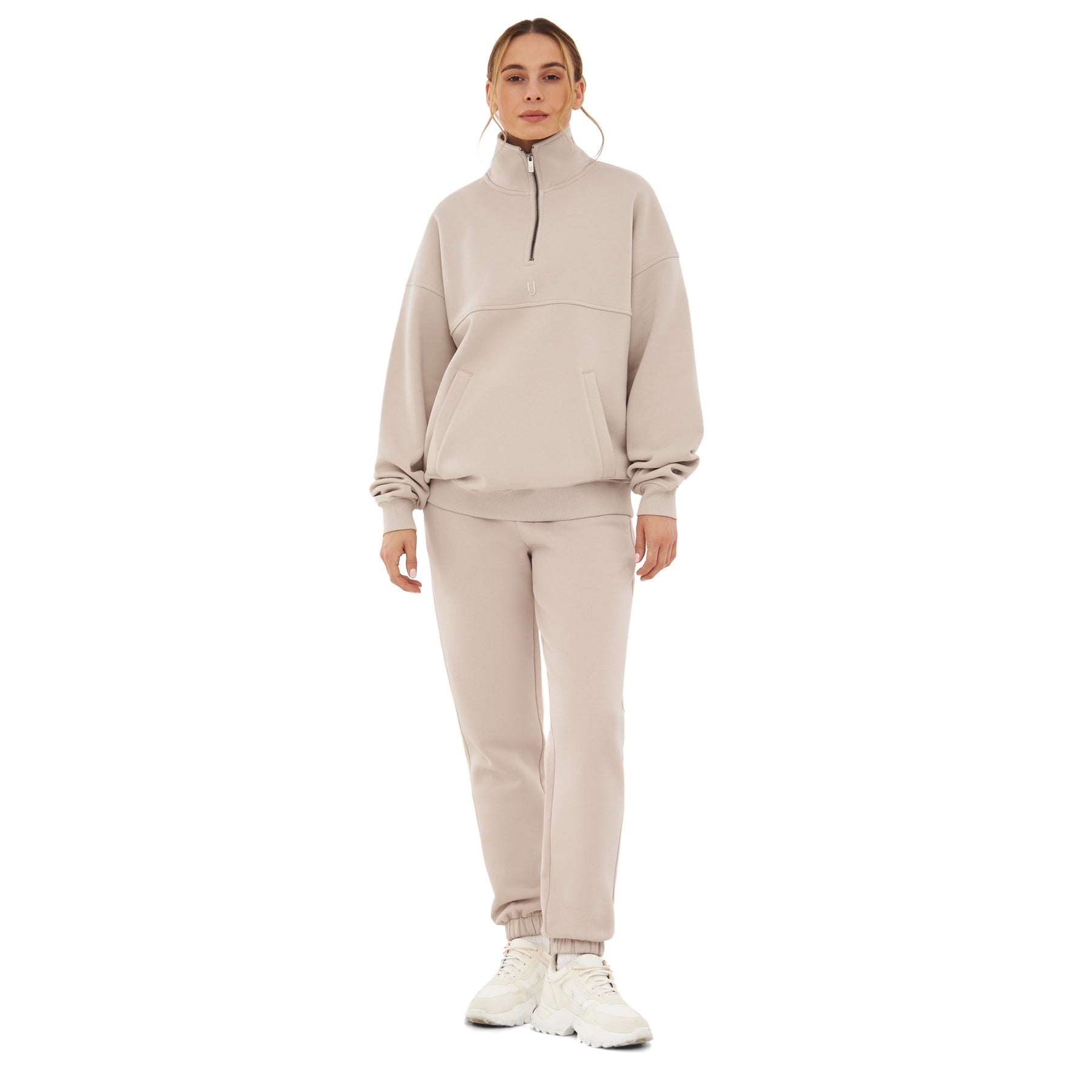 Frau trägt beigen Half-Zip-Sweatshirt 'Cooper' und passende Jogginghose mit weißen Sneakers