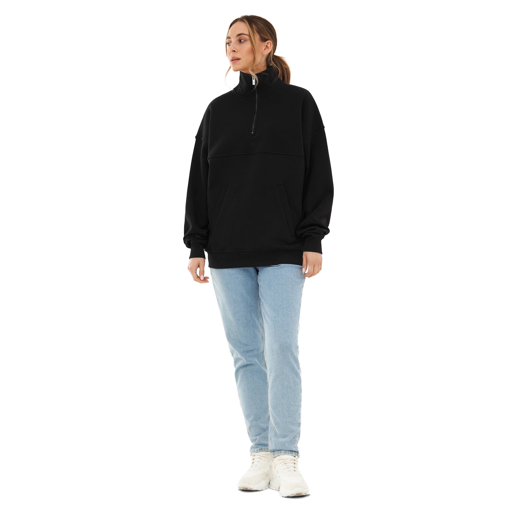Frau trägt schwarzen Half Zip Sweatshirt 'Cooper' mit Stehkragen, kombiniert mit hellblauen Jeans und weißen Schuhen