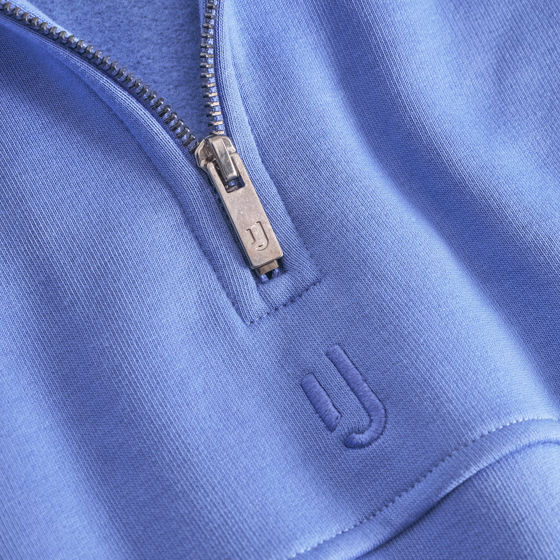 Nahaufnahme eines blauen Half-Zip-Sweatshirts 'Cooper' von Johnny Urban mit geprägtem Logo und silbernem Reißverschluss