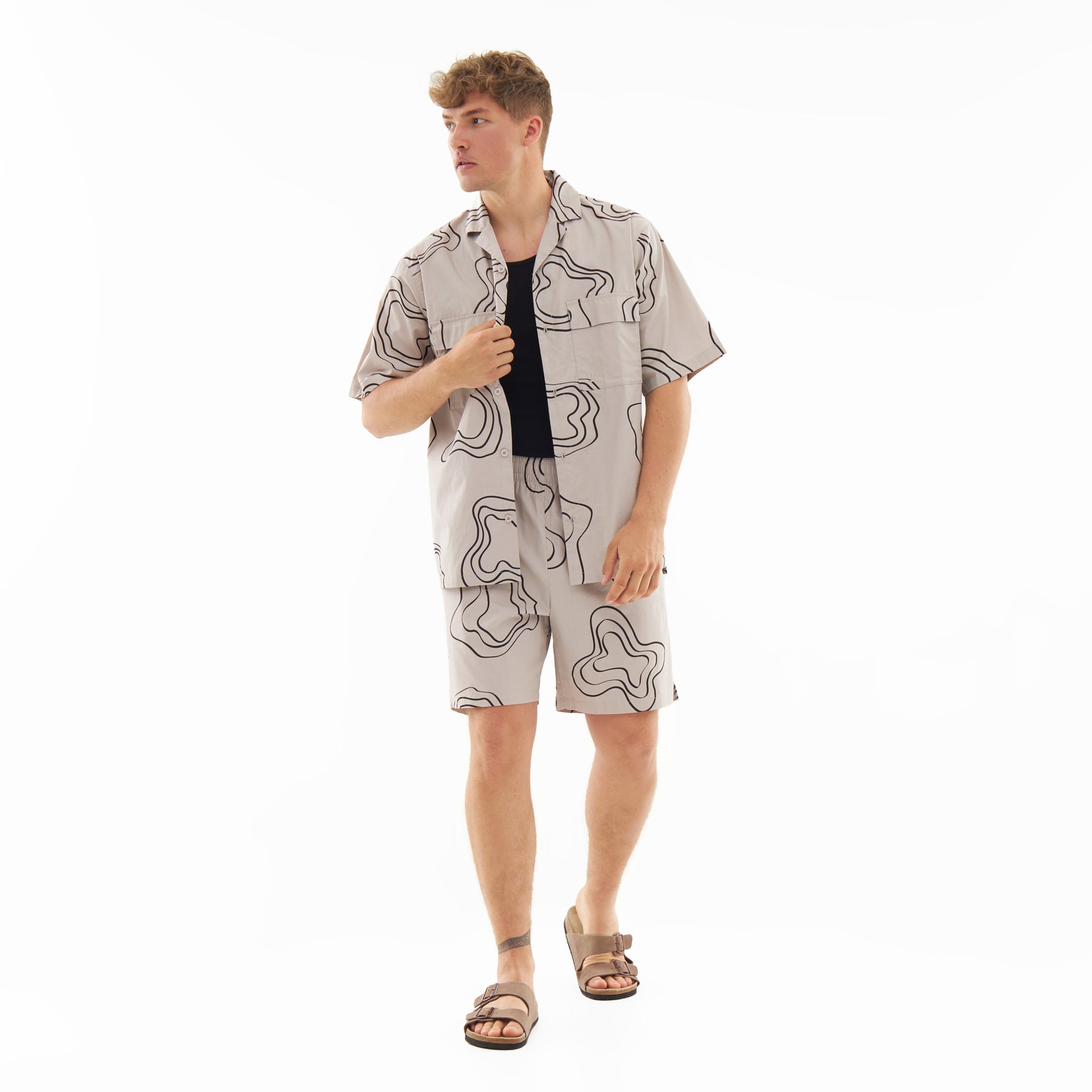 Mann trägt sandfarbenes Hemd und Shorts mit schwarzem abstraktem Muster aus Set 'Spencer'