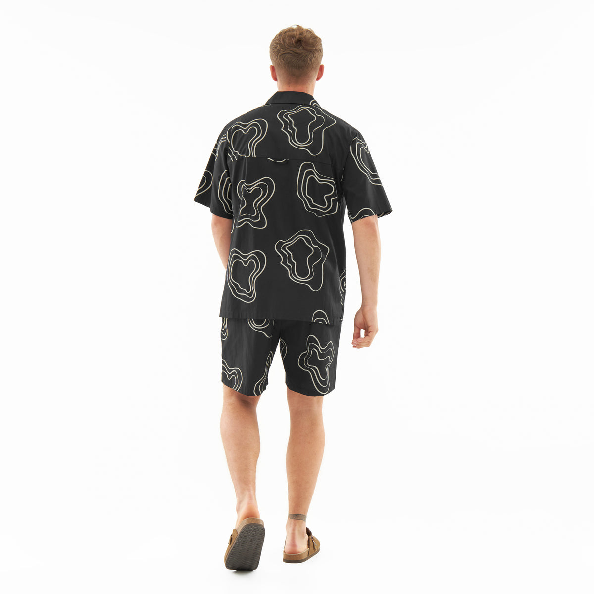 Mann von hinten mit schwarzem Hemd und Shorts mit weißem, abstraktem Muster aus Set 'Spencer'