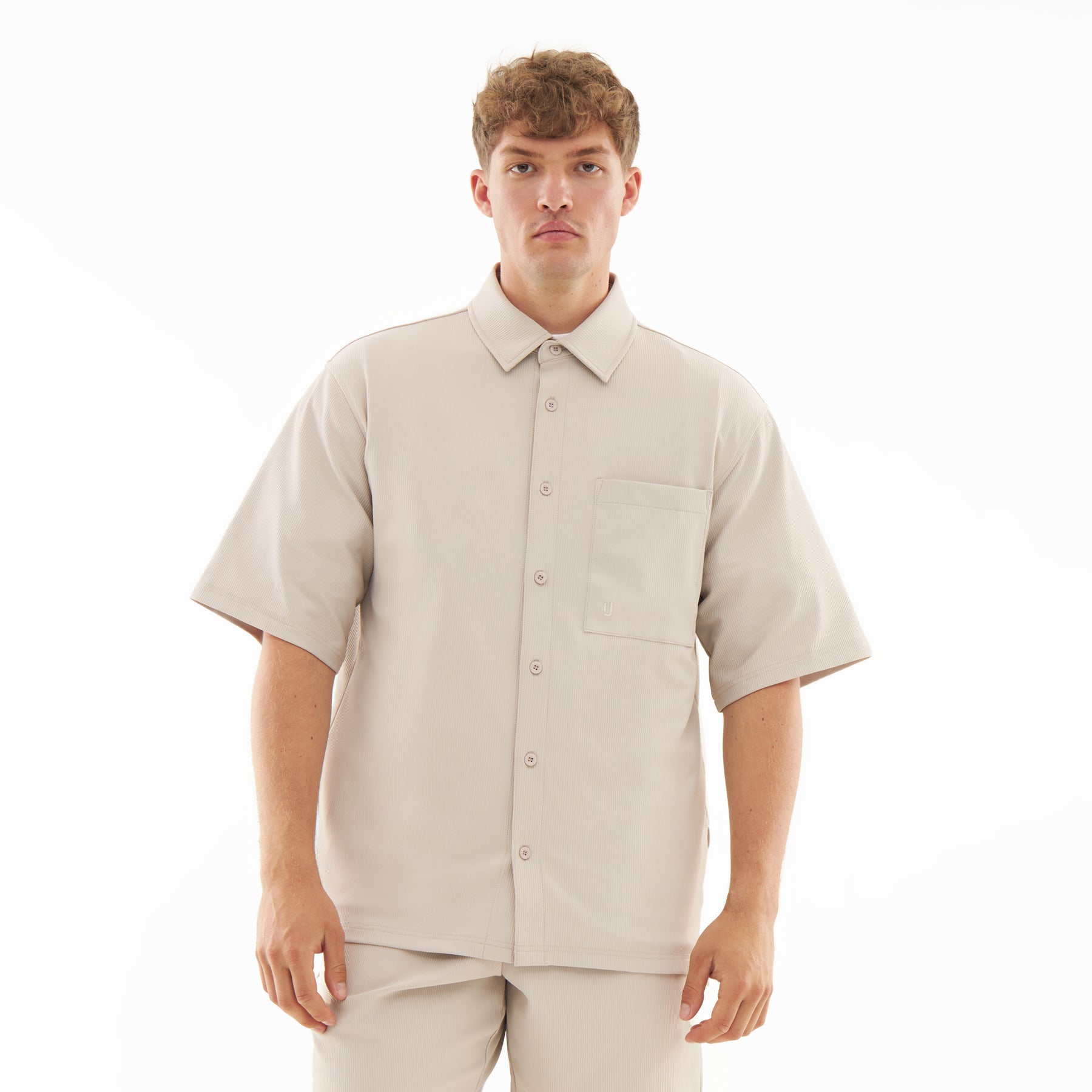 Männliches Modell trägt locker sitzendes, beiges Hemd mit kurzen Ärmeln und Knopfleiste