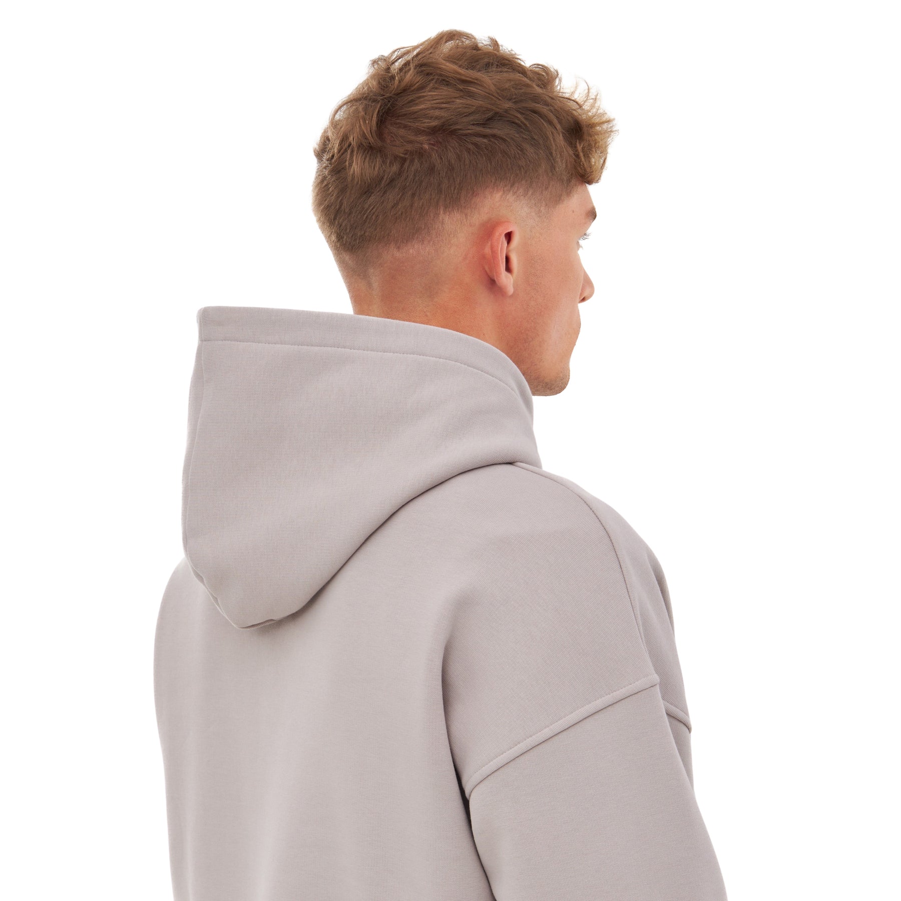 Rückansicht eines Mannes mit kurzem, lockigem Haar, der den oversized Hoodie 'Cody' in Grau trägt