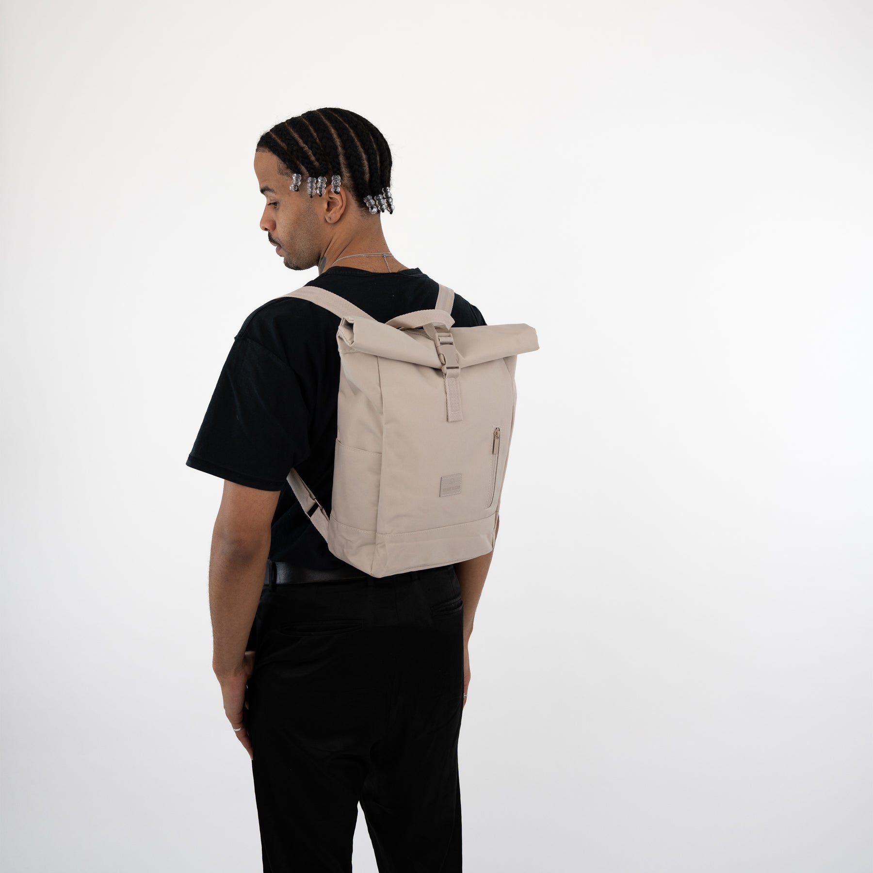 Mann trägt beigen Rolltop Rucksack 'Robin Small' von Johnny Urban, schwarze Kleidung