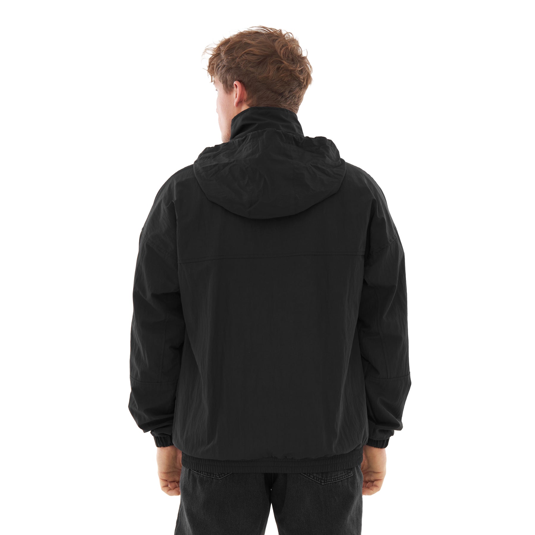 Mann trägt schwarze Übergangsjacke 'Lennon' von hinten mit Kapuze, schwarze Hose