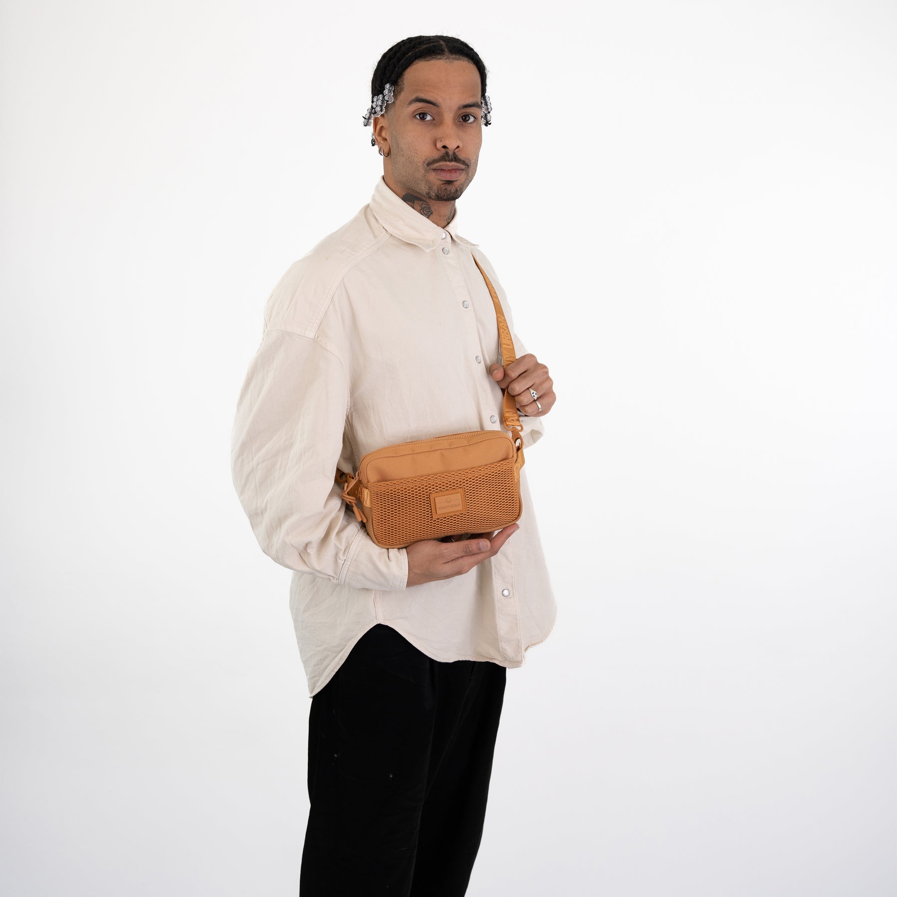 Mann in beige Hemd trägt karamellfarbene Umhängetasche „Elliot“ mit Netzfach