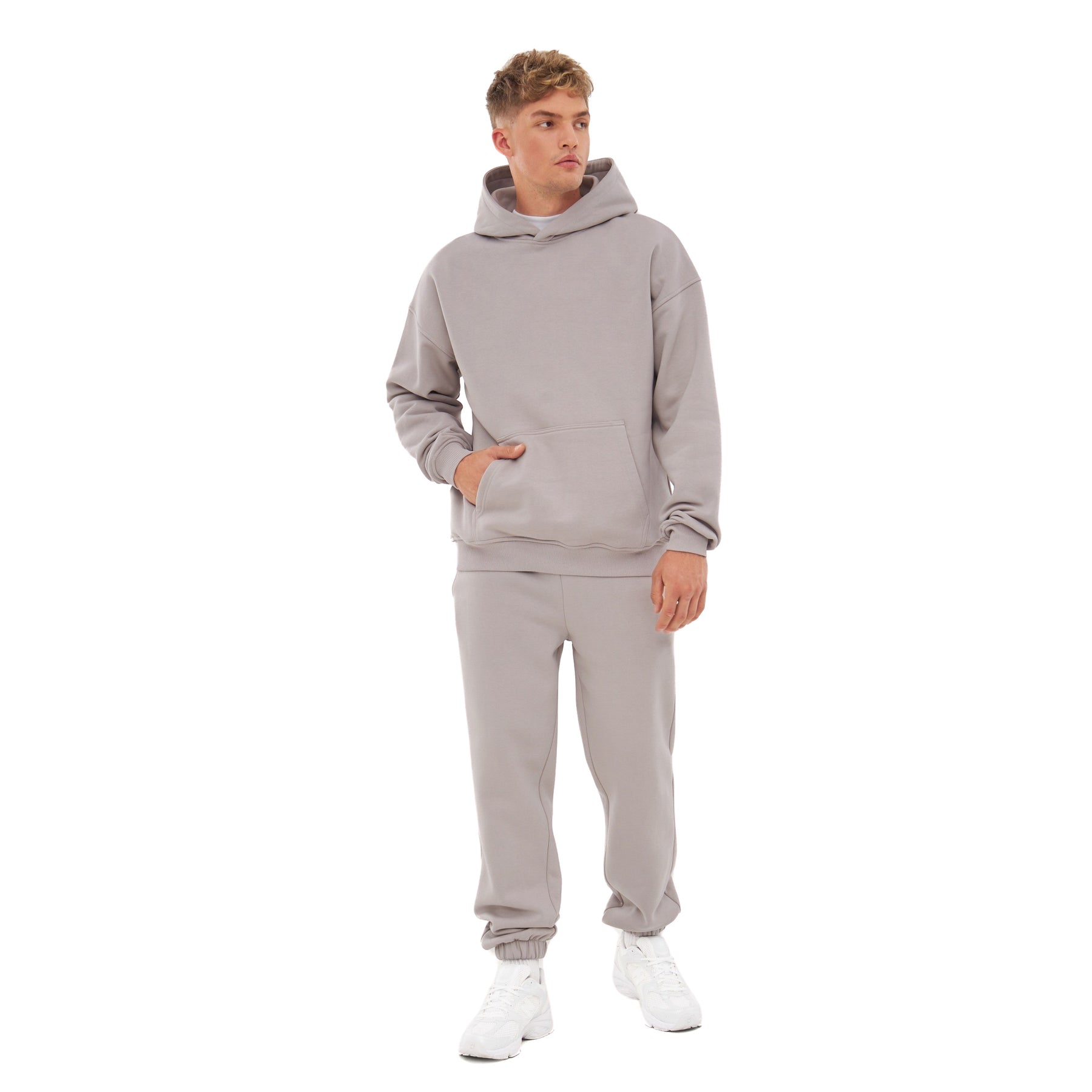 Mann trägt beige Oversized Hoodie 'Cody' und passende Jogginghose mit weißen Sneakers