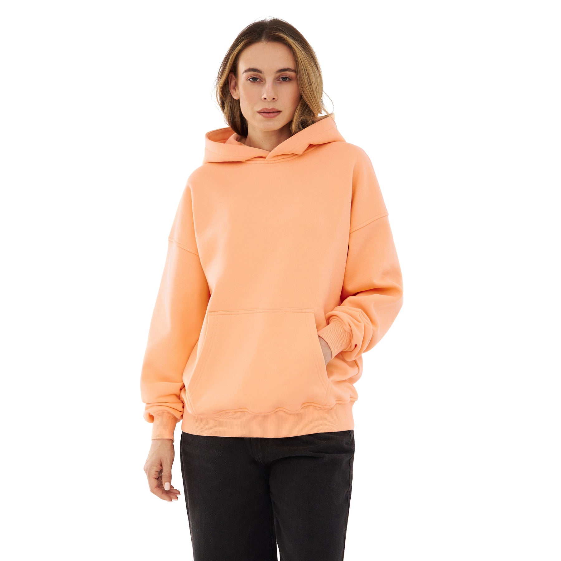 Frau trägt oversized Hoodie 'Cody' in Pfirsichfarben mit Kängurutasche und Kapuze