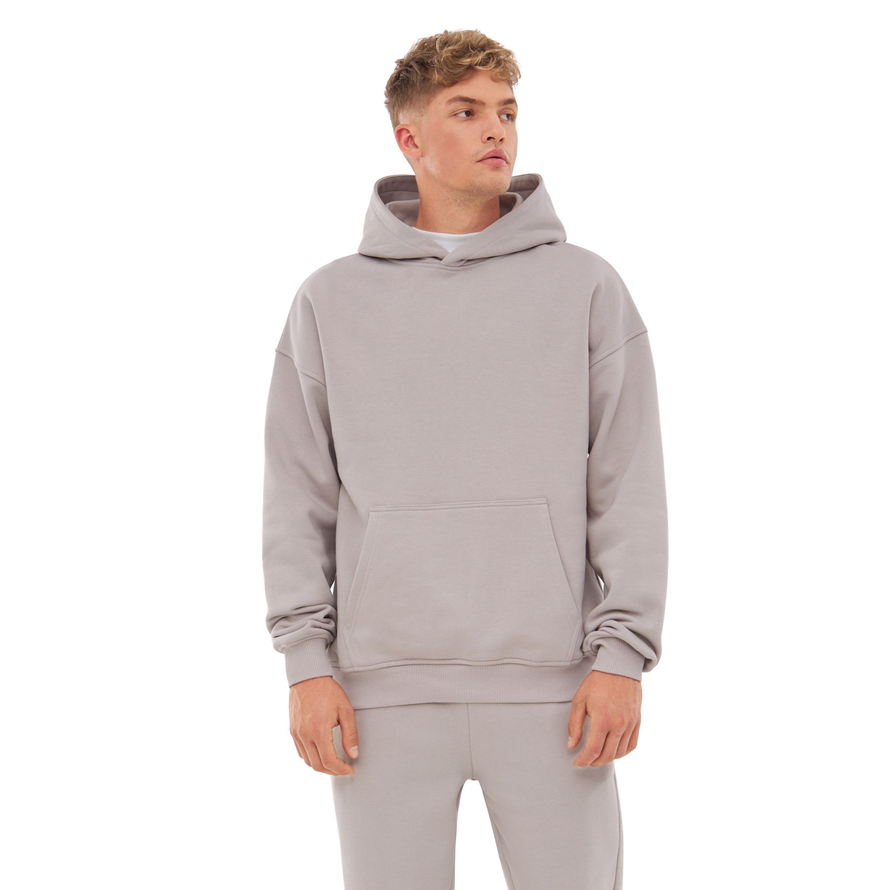 Mann trägt oversized Hoodie 'Cody' in Beige mit Kängurutasche und lockerem Sitz