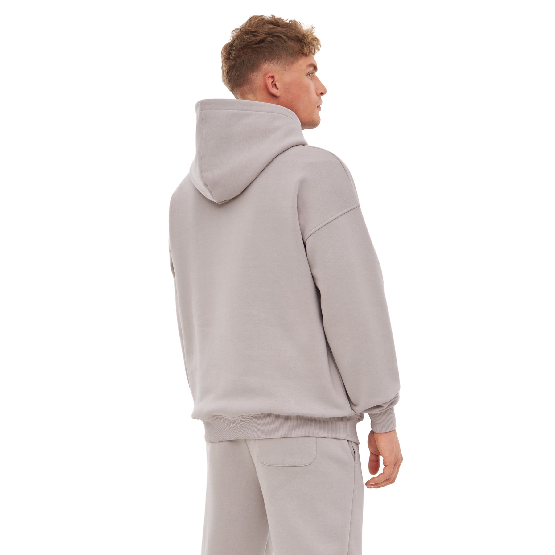 Mann trägt oversized Hoodie 'Cody' in warmem Grau, Ansicht von hinten