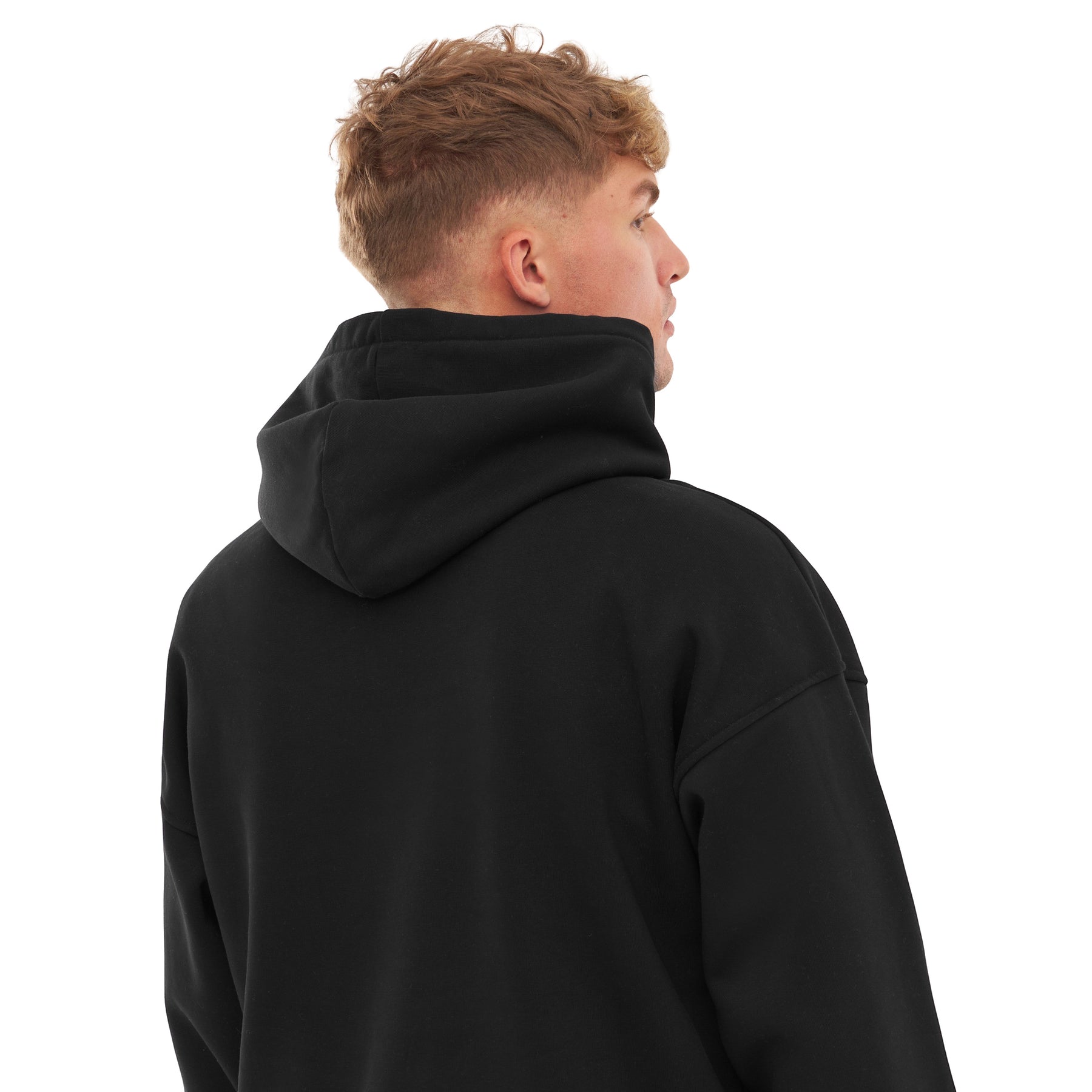 Rückansicht eines Mannes mit kurzem, blondem Haar, der einen schwarzen, oversized Hoodie namens 'Cody' trägt
