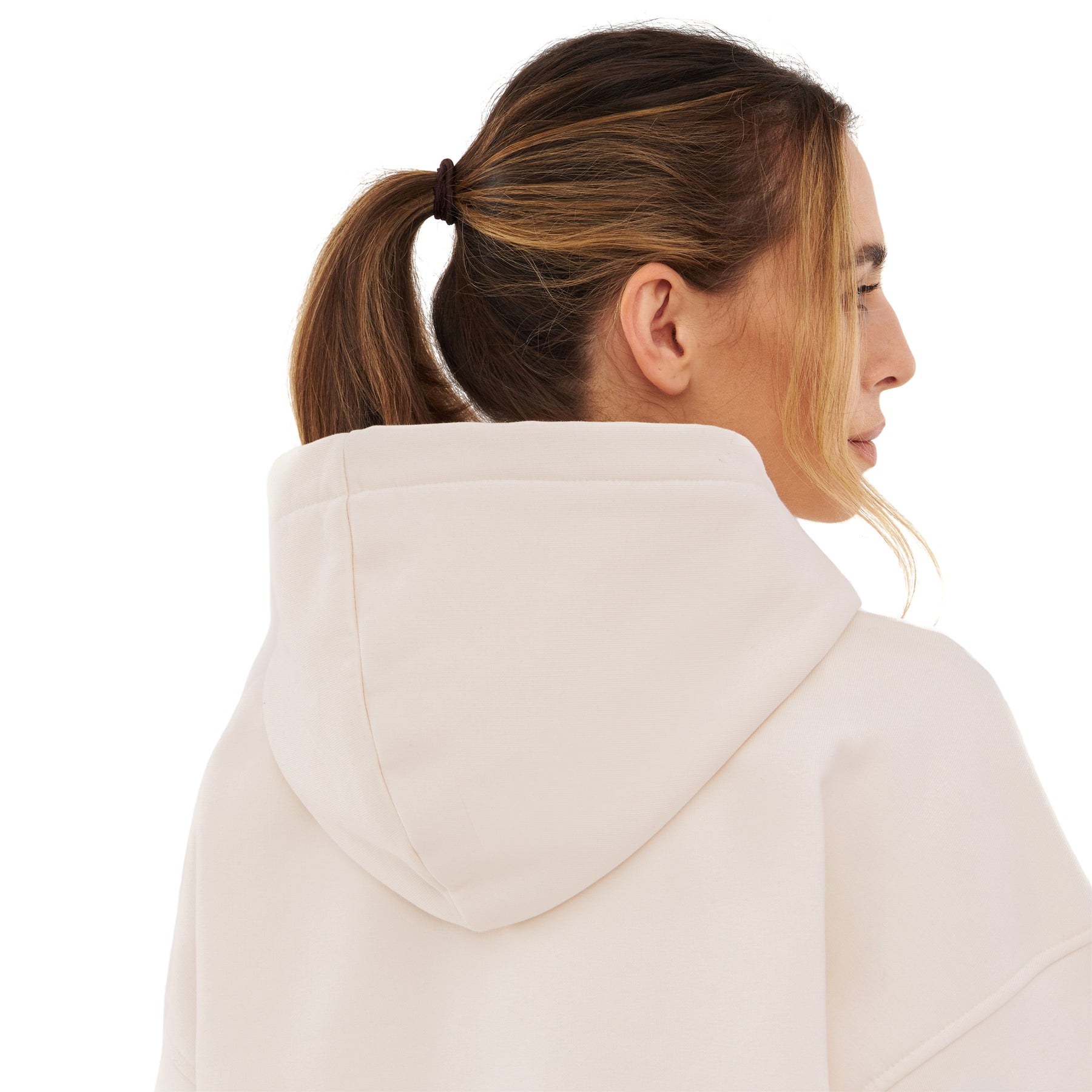 Frau mit zusammengebundenem Haar trägt oversized Hoodie 'Cody' in hellem Beige, Rückansicht mit Kapuze