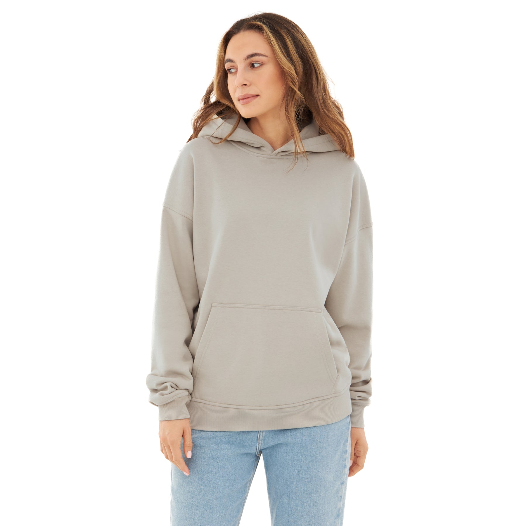 Frau trägt beigen Oversized Hoodie 'Cody' mit Kapuze und Kängurutasche, kombiniert mit blauen Jeans