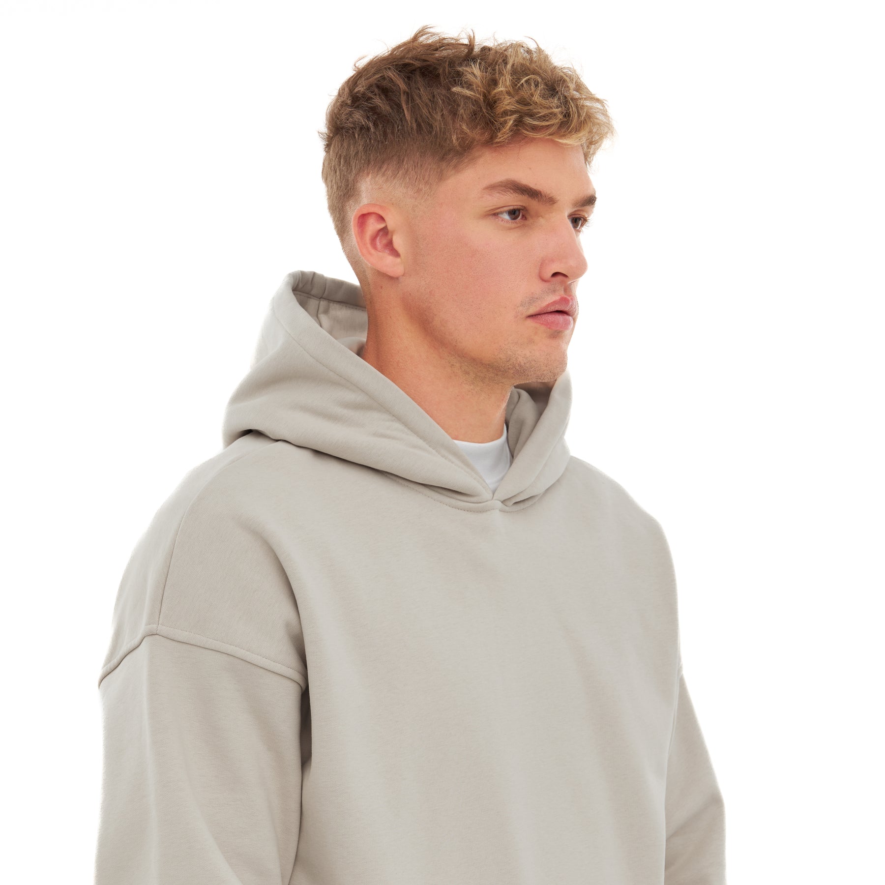 Mann mit kurzem blondem Haar trägt einen oversized Hoodie 'Cody' in hellem Beige mit Kapuze
