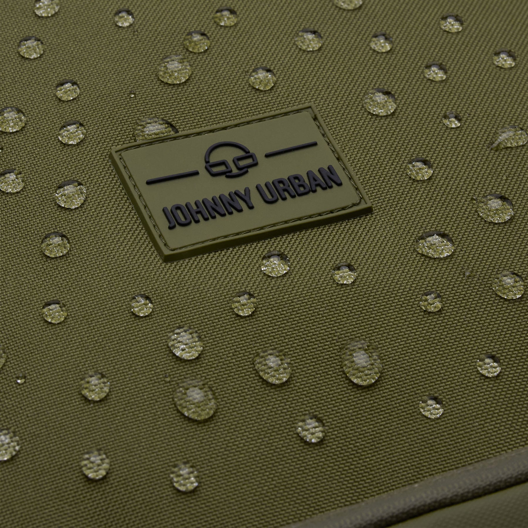Nahaufnahme des wasserabweisenden Stoffs und des Johnny Urban Logos auf dem Rolltop Rucksack Allen XL in Olivgrün