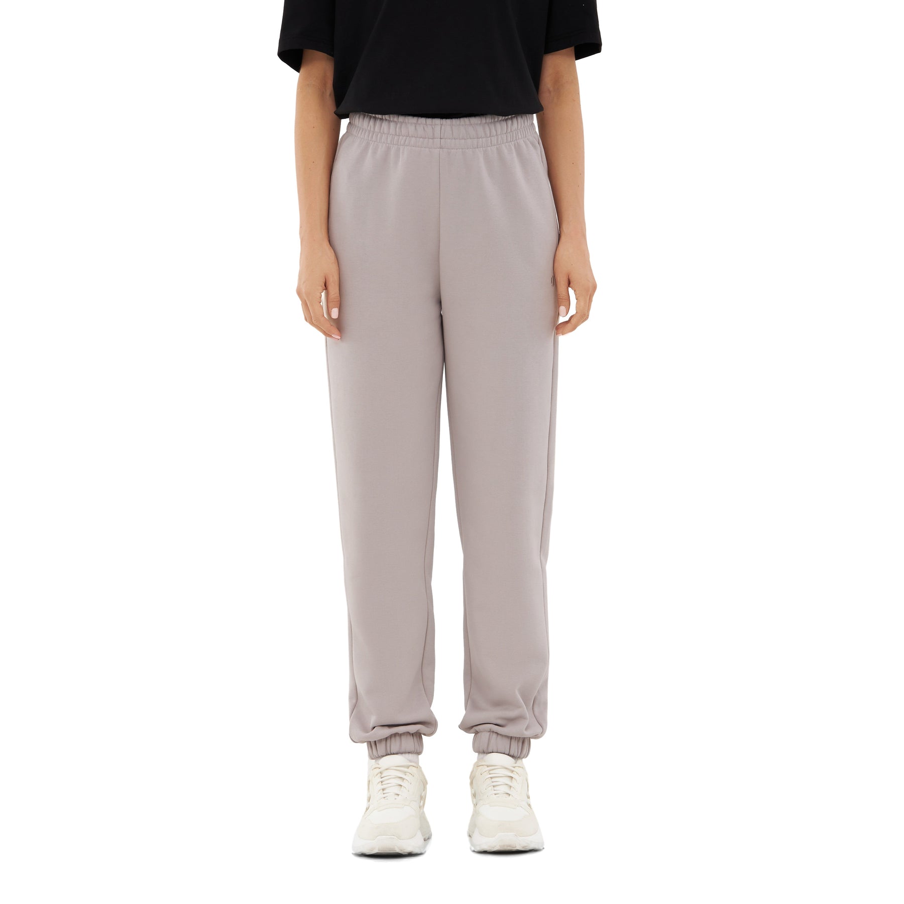 Hose 'Owen' Jogginghose in hellgrau mit elastischem Bund und Bündchen am Knöchel, kombiniert mit schwarzem T-Shirt und weißen Sneakers