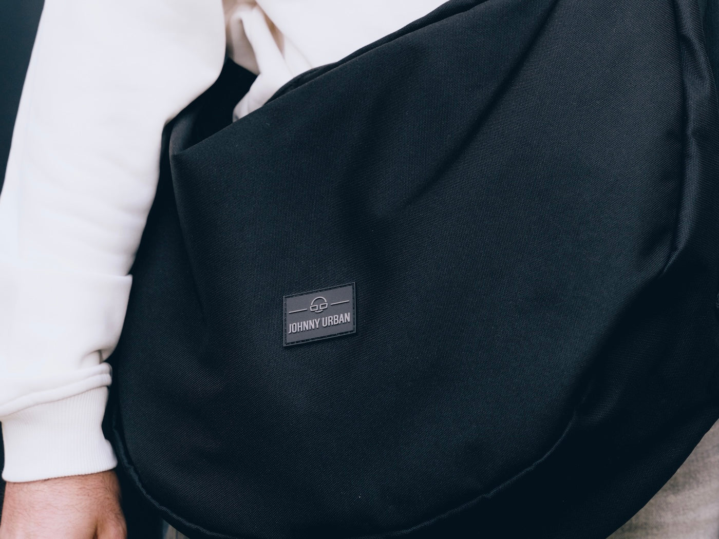 Schwarze Half Moon Bag 'Ally Medium' von Johnny Urban aus robustem Material getragen von Person mit weißem Sweatshirt