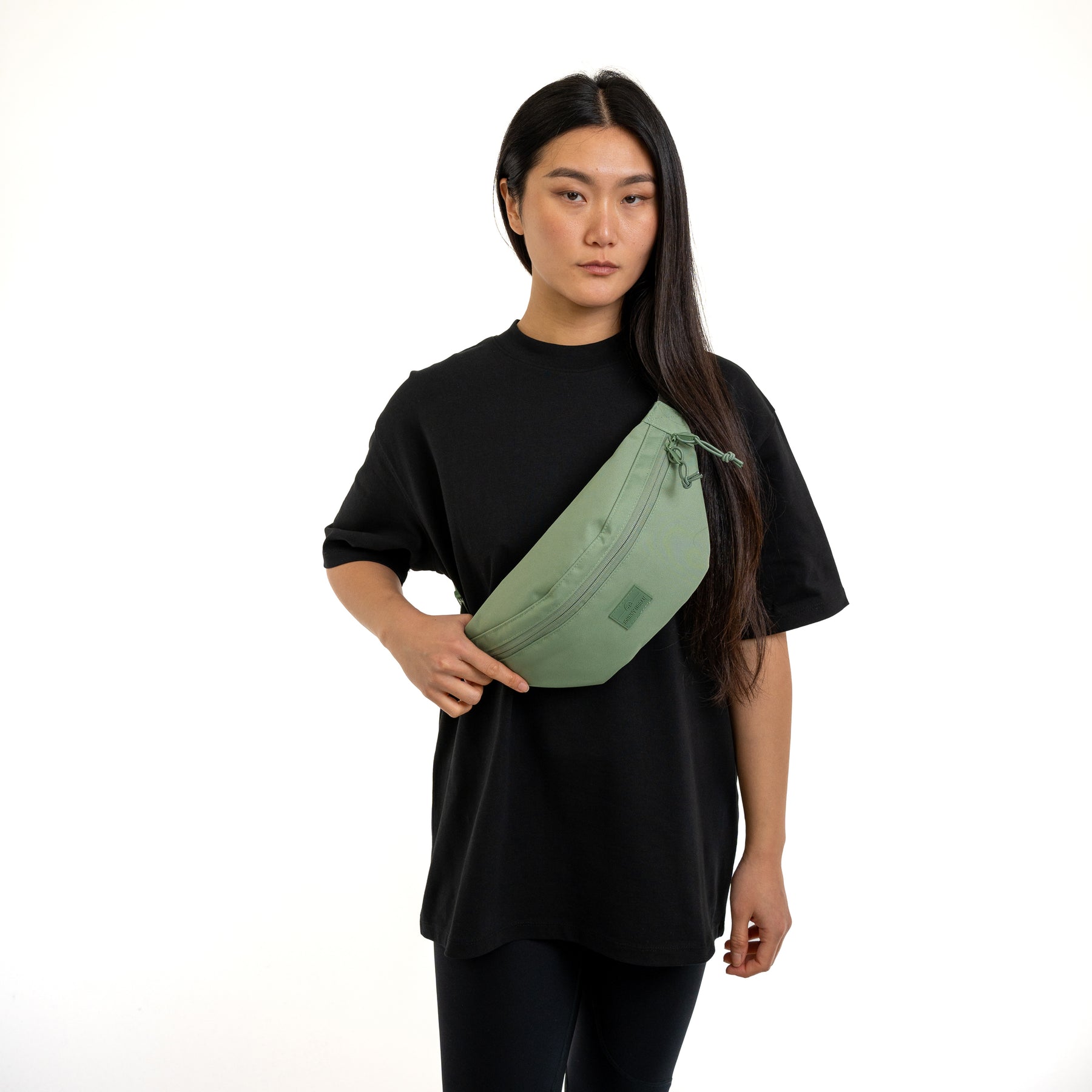 Frau trägt sage-green Bauchtasche 'Erik Large' von Johnny Urban über der Schulter mit schwarzem Shirt