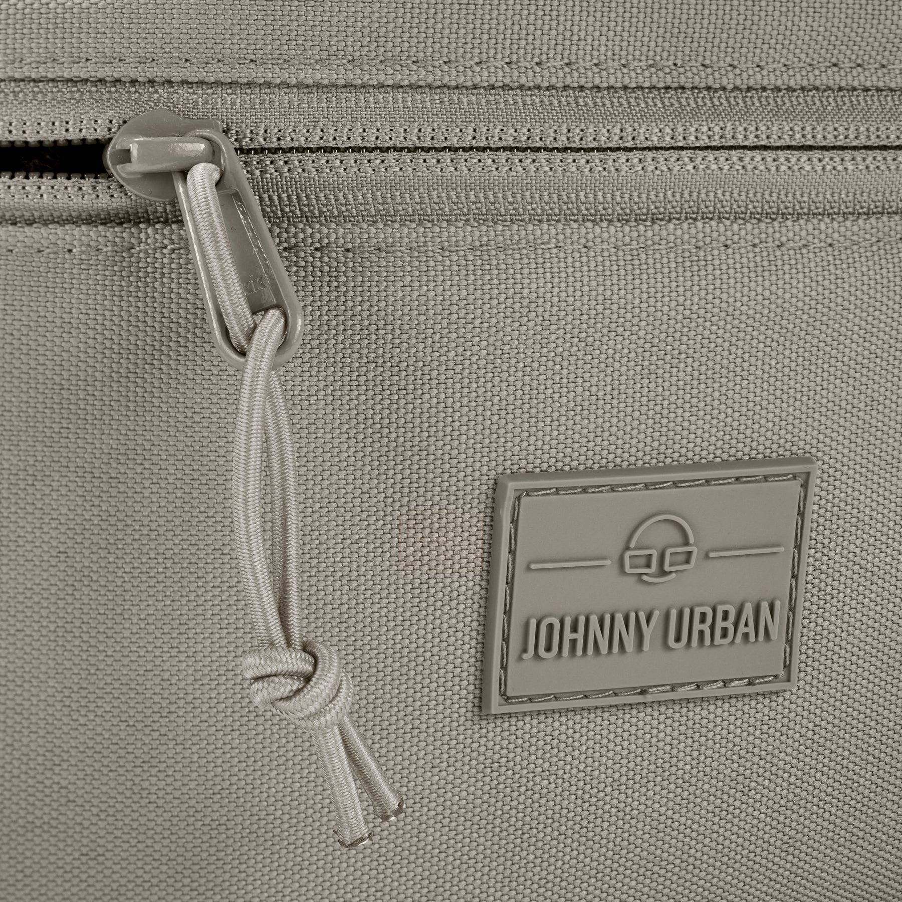 Detailansicht eines Reißverschlusses und des Johnny Urban Logos auf der Bauchtasche 'Erik Large' in desert grey