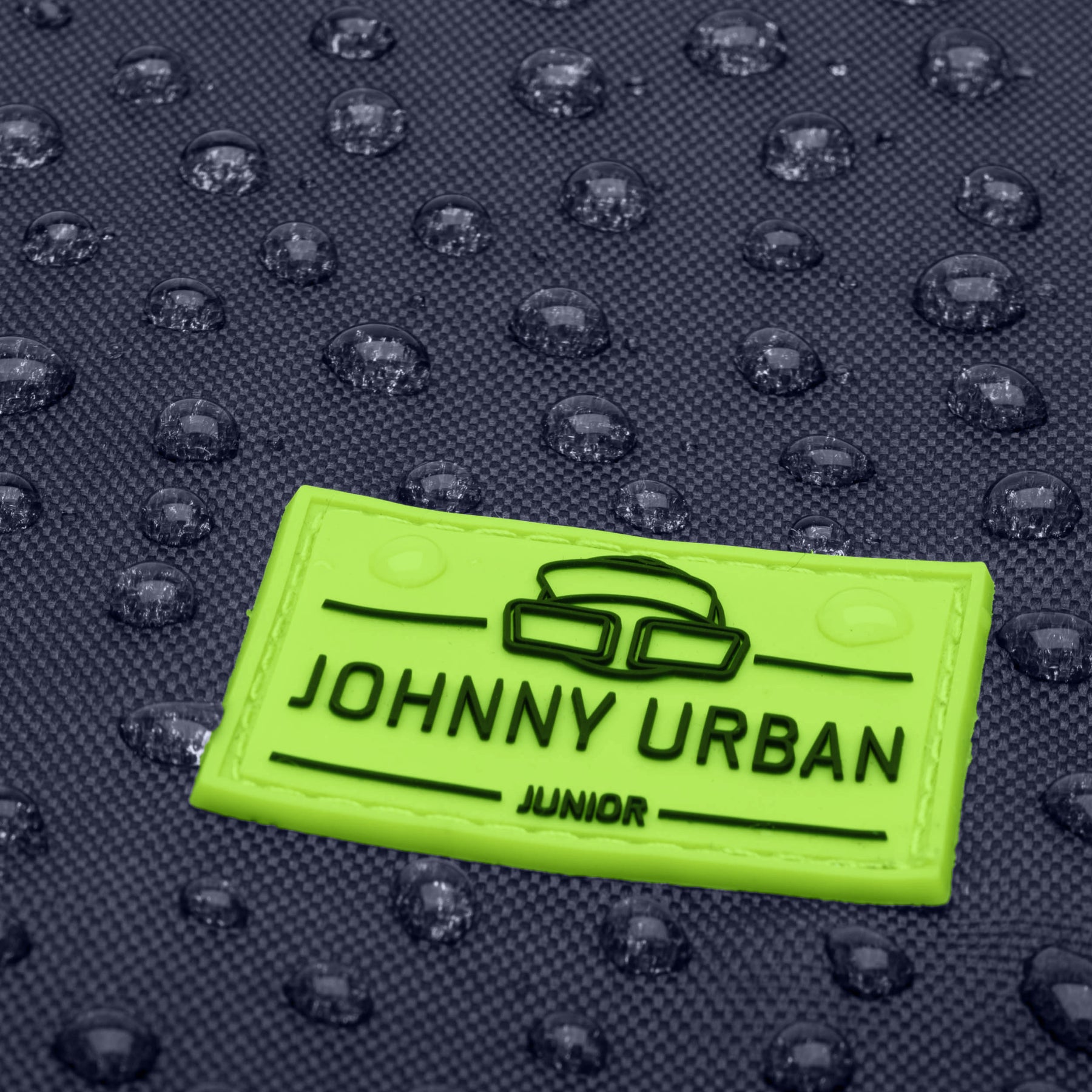 Nahe Aufnahme eines wasserabweisenden, dunkelblauen Kinder-Turnbeutels mit neongrünem Aufnäher 'Johnny Urban Junior'