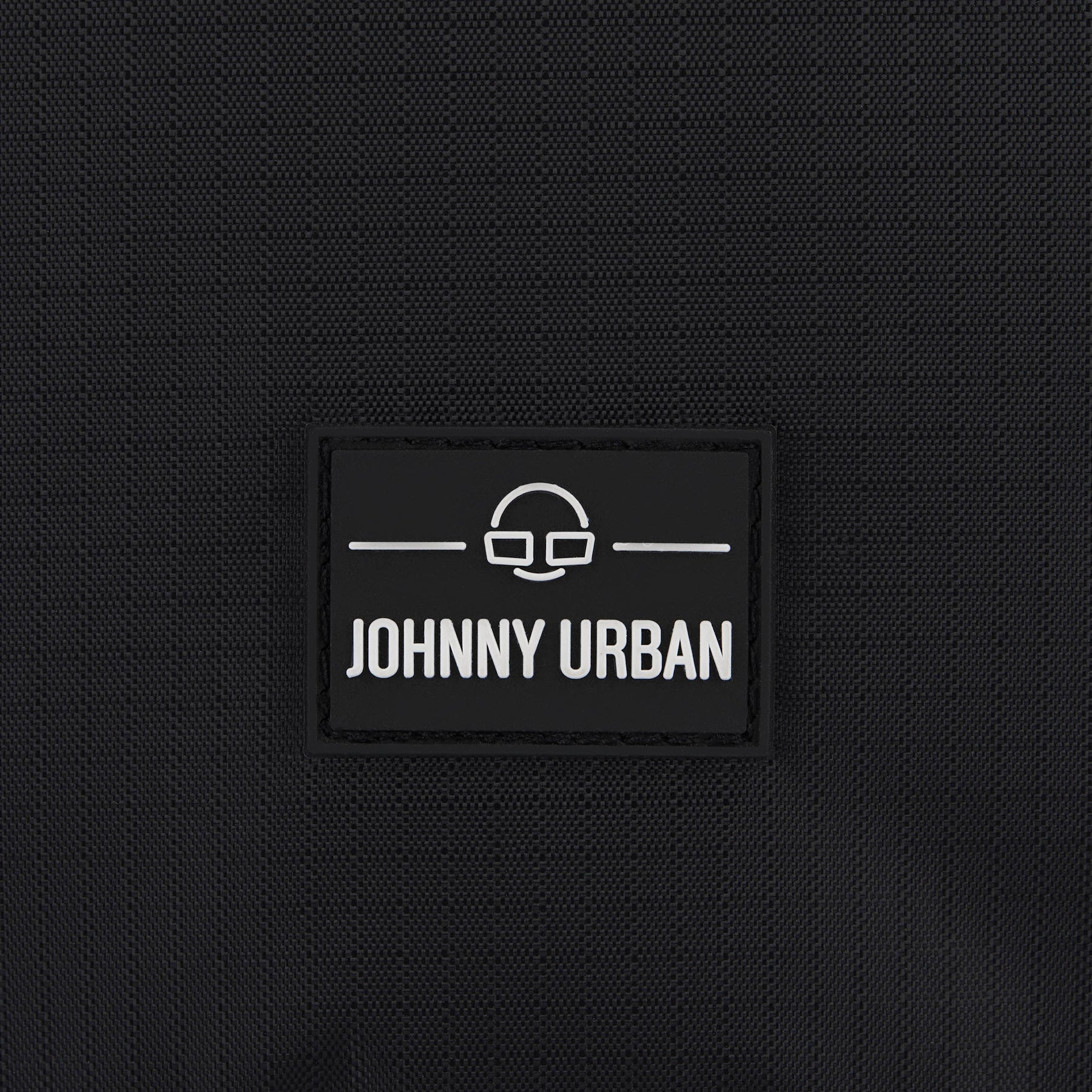 Nahaufnahme des Johnny Urban Logos auf schwarzem Stoff einer Kulturtasche