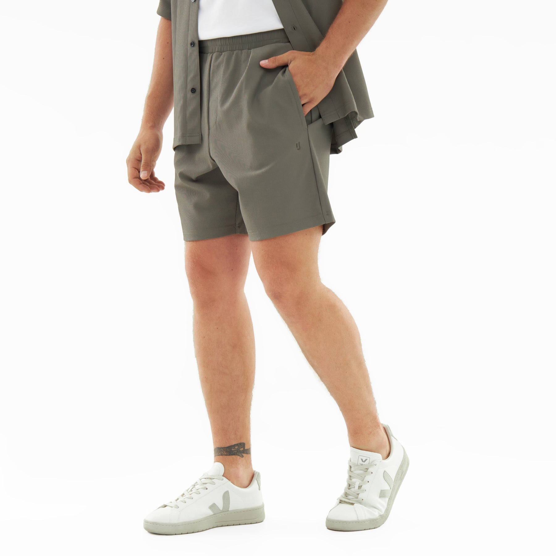 Männliche Beine mit olivgrüner Mason Shorts aus leichtem Material und weißen Sneakern