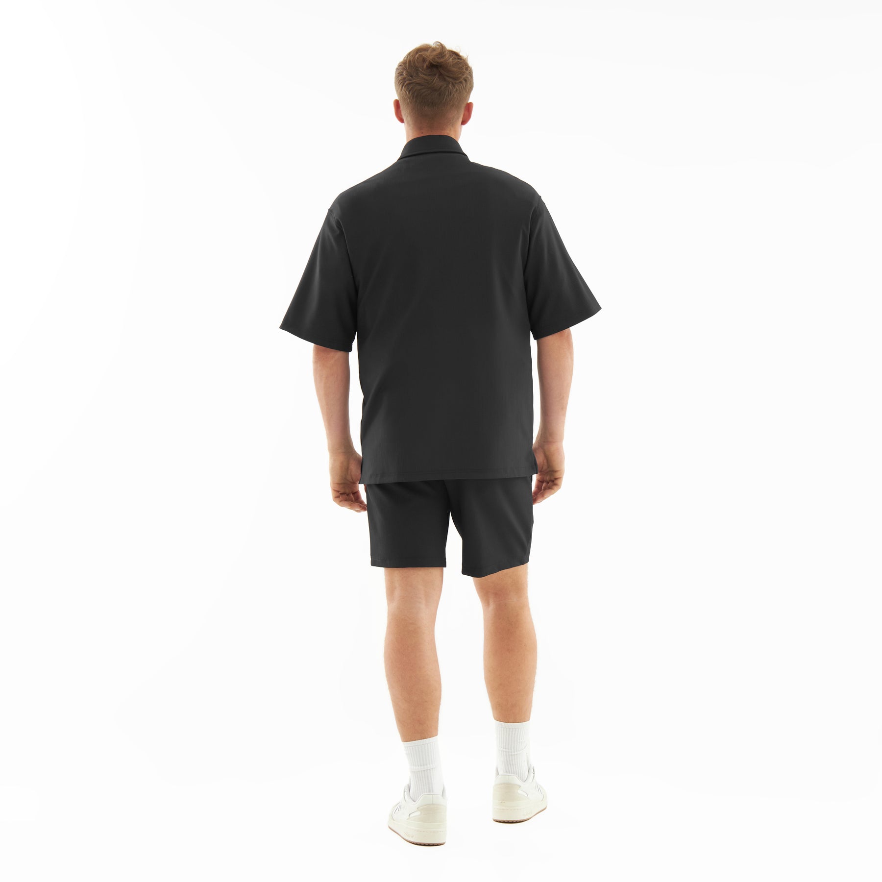Mann trägt schwarze lockere Herren-Shorts 'Mason' und schwarzes Kurzarmhemd von hinten
