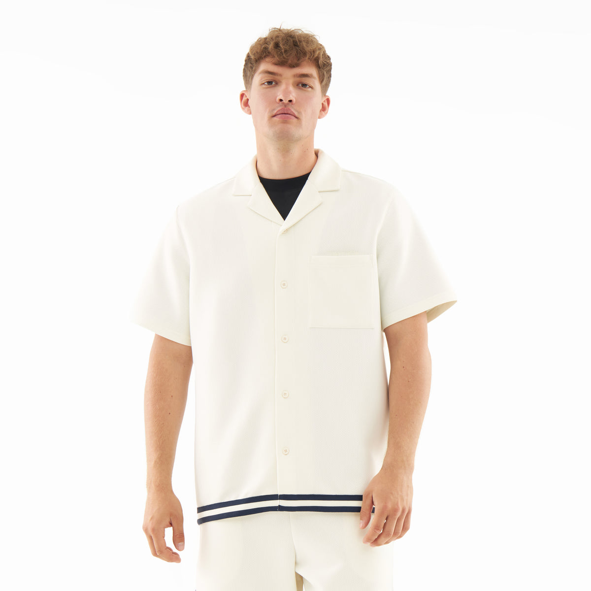 Mann trägt cremefarbenes, leichtes Kurzarmhemd mit Kragen und schwarzem Streifen am Saum aus Set 'Parker'