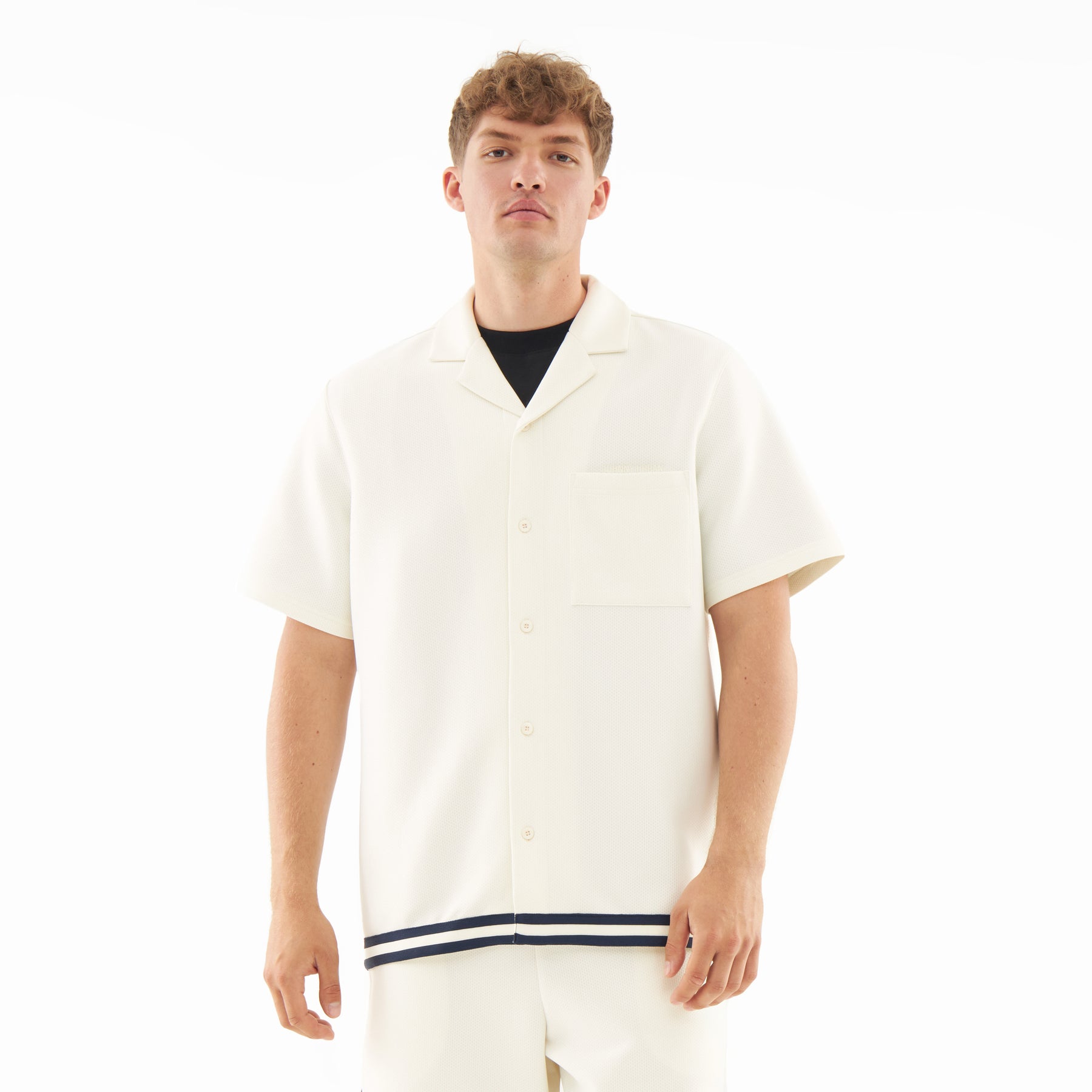 Mann trägt cremefarbenes, leichtes Kurzarmhemd mit Kragen und schwarzem Streifen am Saum aus Set 'Parker'