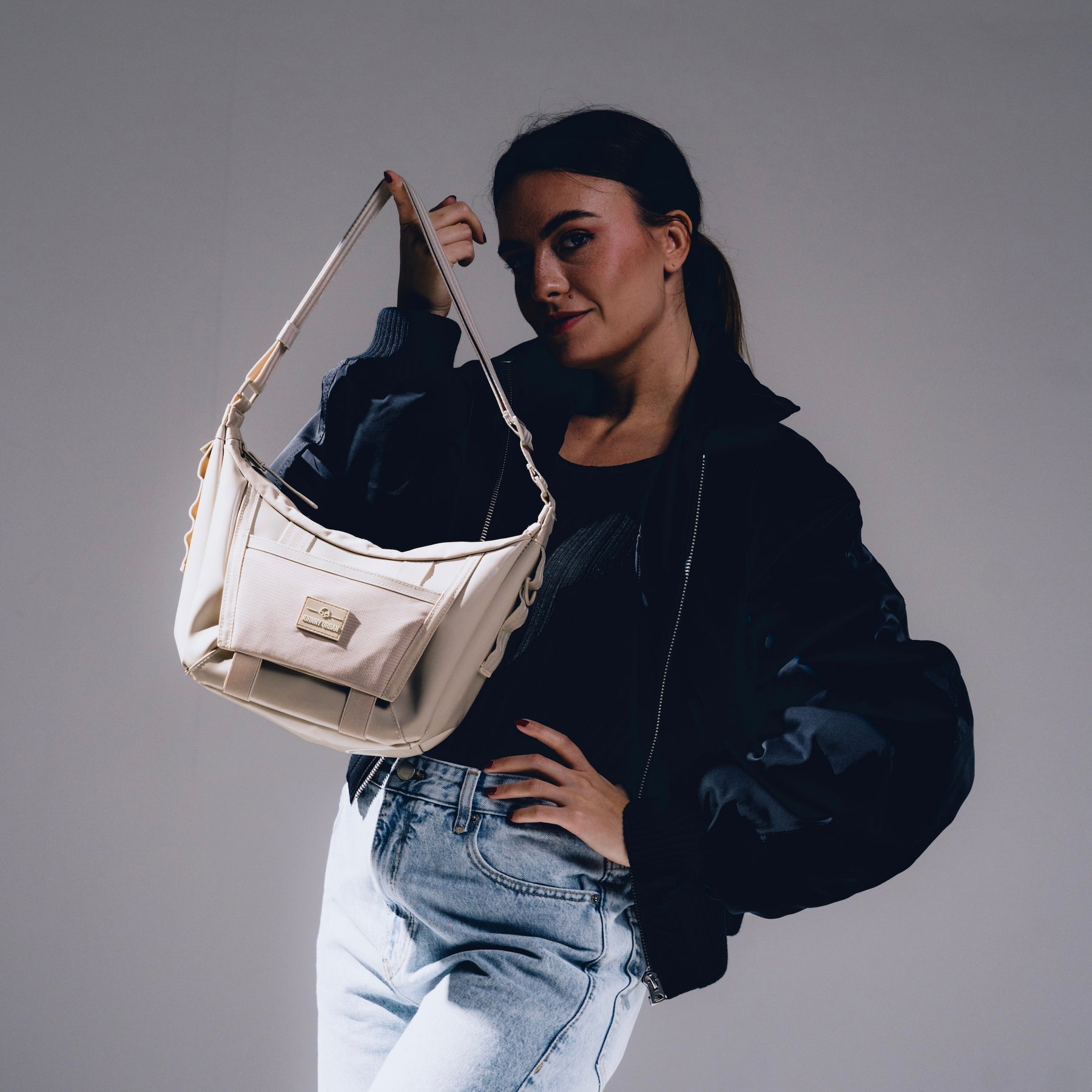 Frau mit schwarzer Jacke und Jeans hält beige Handtasche 'Liv'