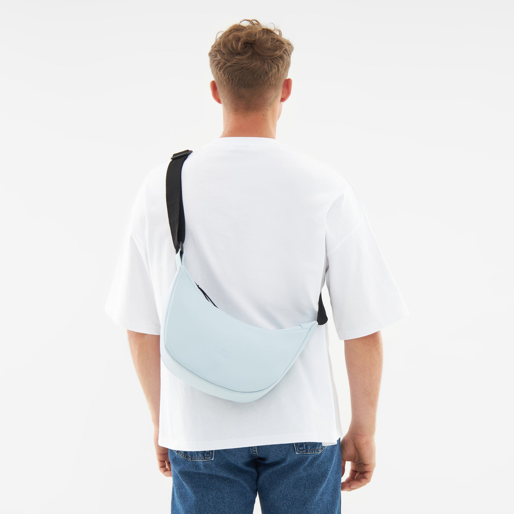 Hellblau Halbmondtasche 'Rory' von Johnny Urban quer getragen am Rücken eines Mannes mit weißem T-Shirt und blauen Jeans