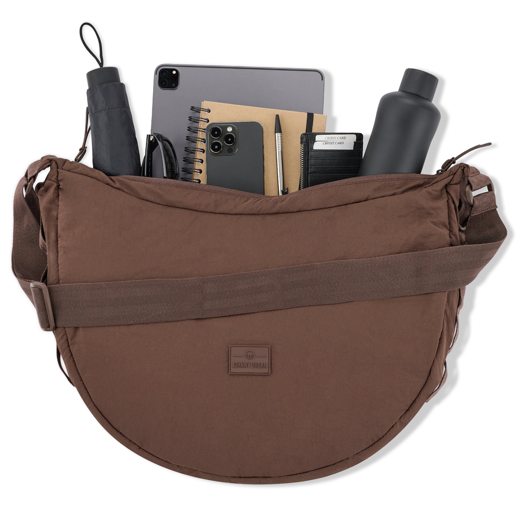 Halbmondtasche Kaia XL von Johnny Urban in Braun mit Laptop, Smartphone, Notizbuch, Stift, Kreditkartenetui, Wasserflasche, Regenschirm und Sonnenbrille gefüllt