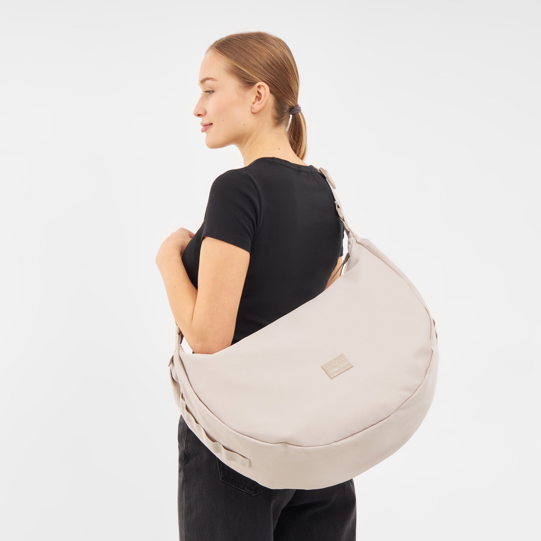 Frau trägt halbrunde Umhängetasche 'Ally XL' in hellem Beige über der Schulter
