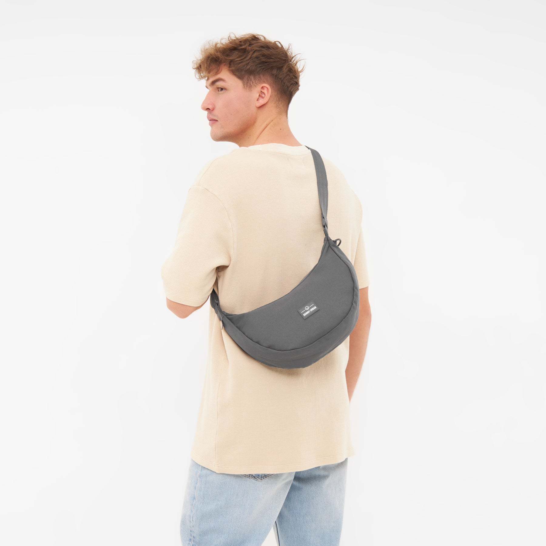 Mann trägt die halbmondförmige Tasche 'Ally Medium' von Johnny Urban in Grau über der Schulter