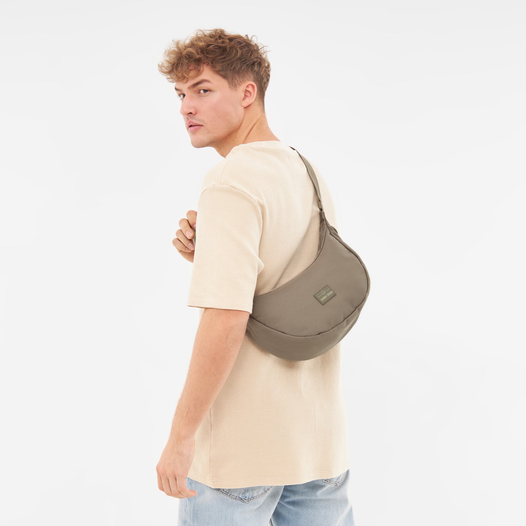 Mann trägt die Half Moon Bag 'Ally Medium' von Johnny Urban in taupe über der Schulter