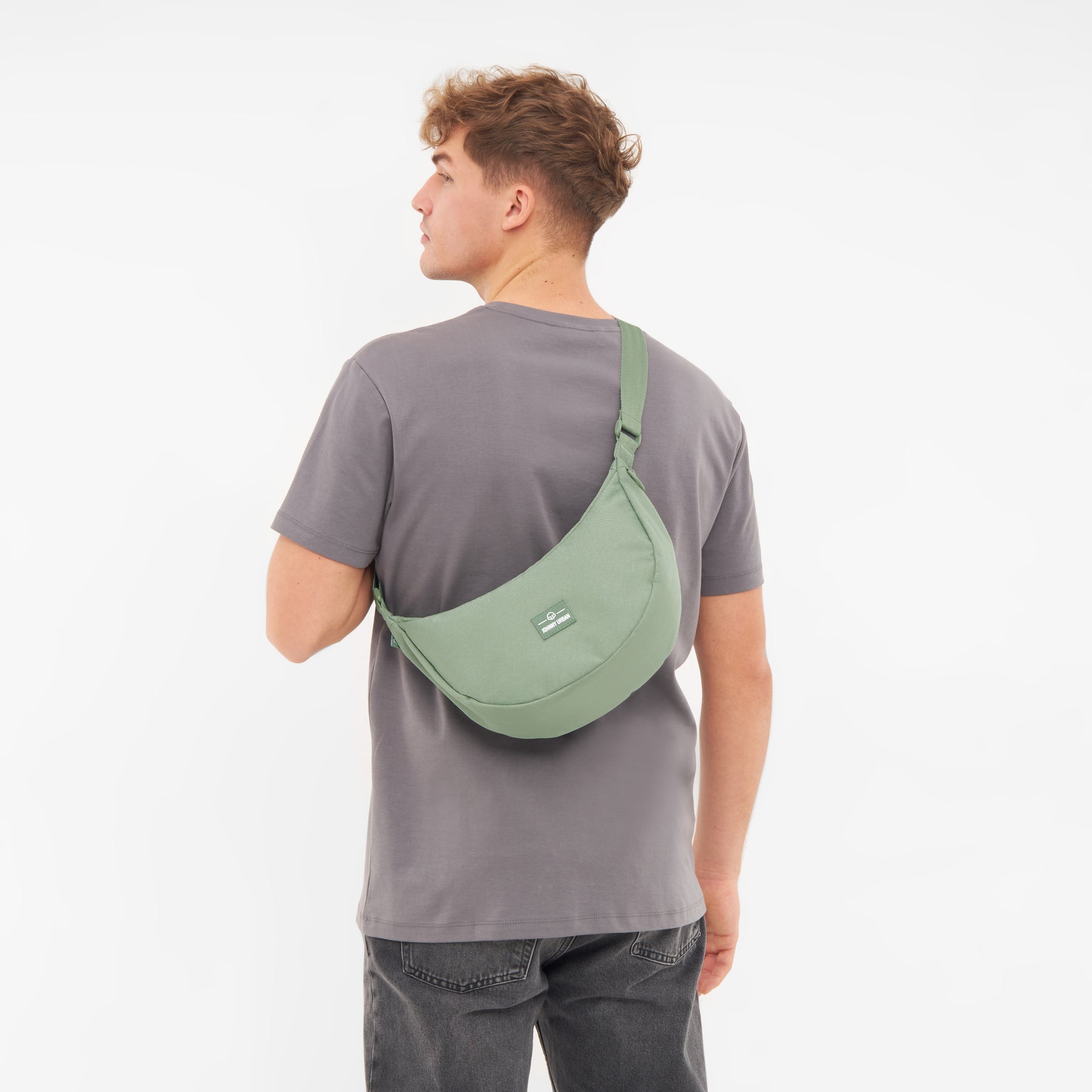 Mann von hinten trägt Half Moon Bag 'Ally Medium' in grün über grauem T-Shirt und dunkler Jeans