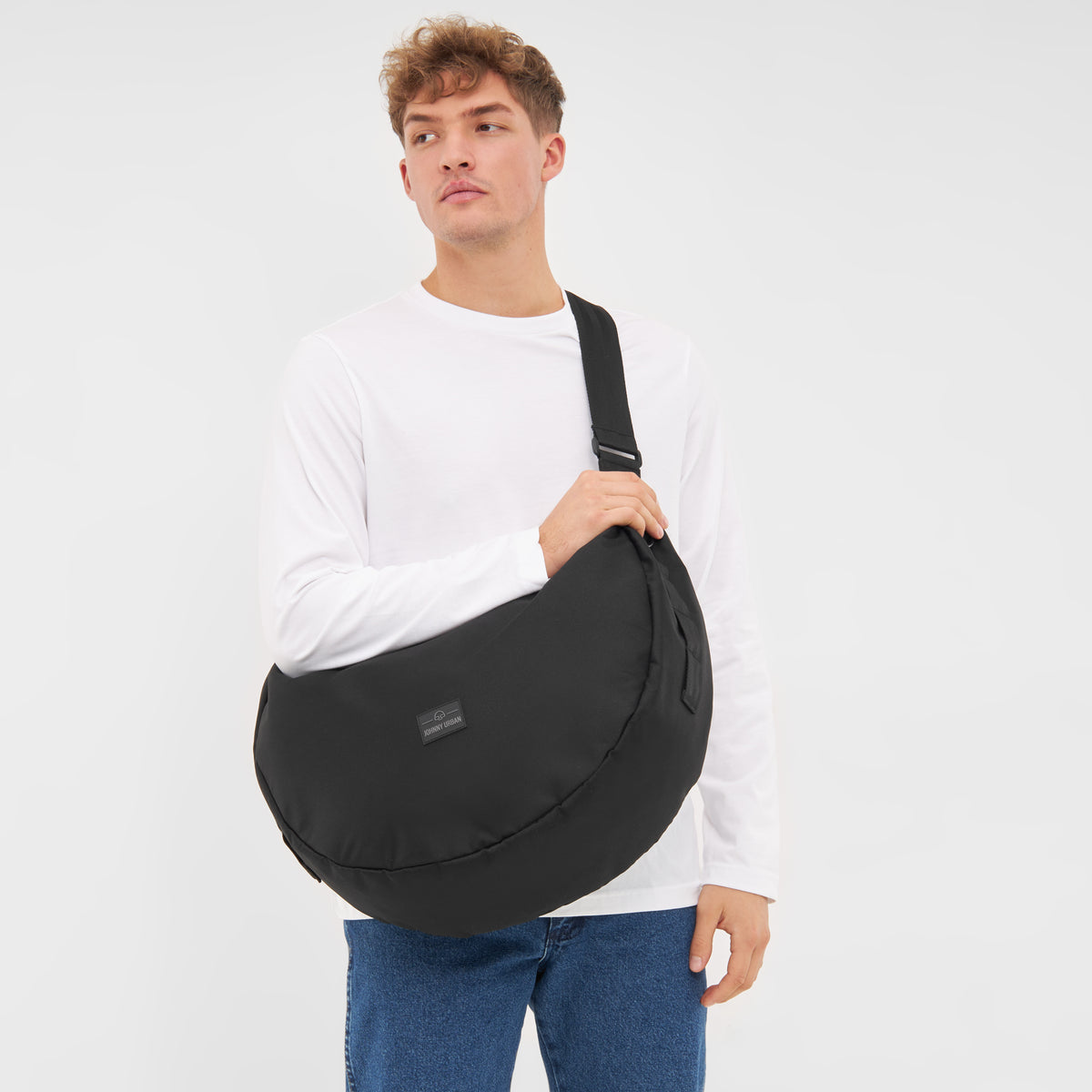 Mann trägt die schwarze Half Moon Bag 'Ally XL' von Johnny Urban quer über die Schulter