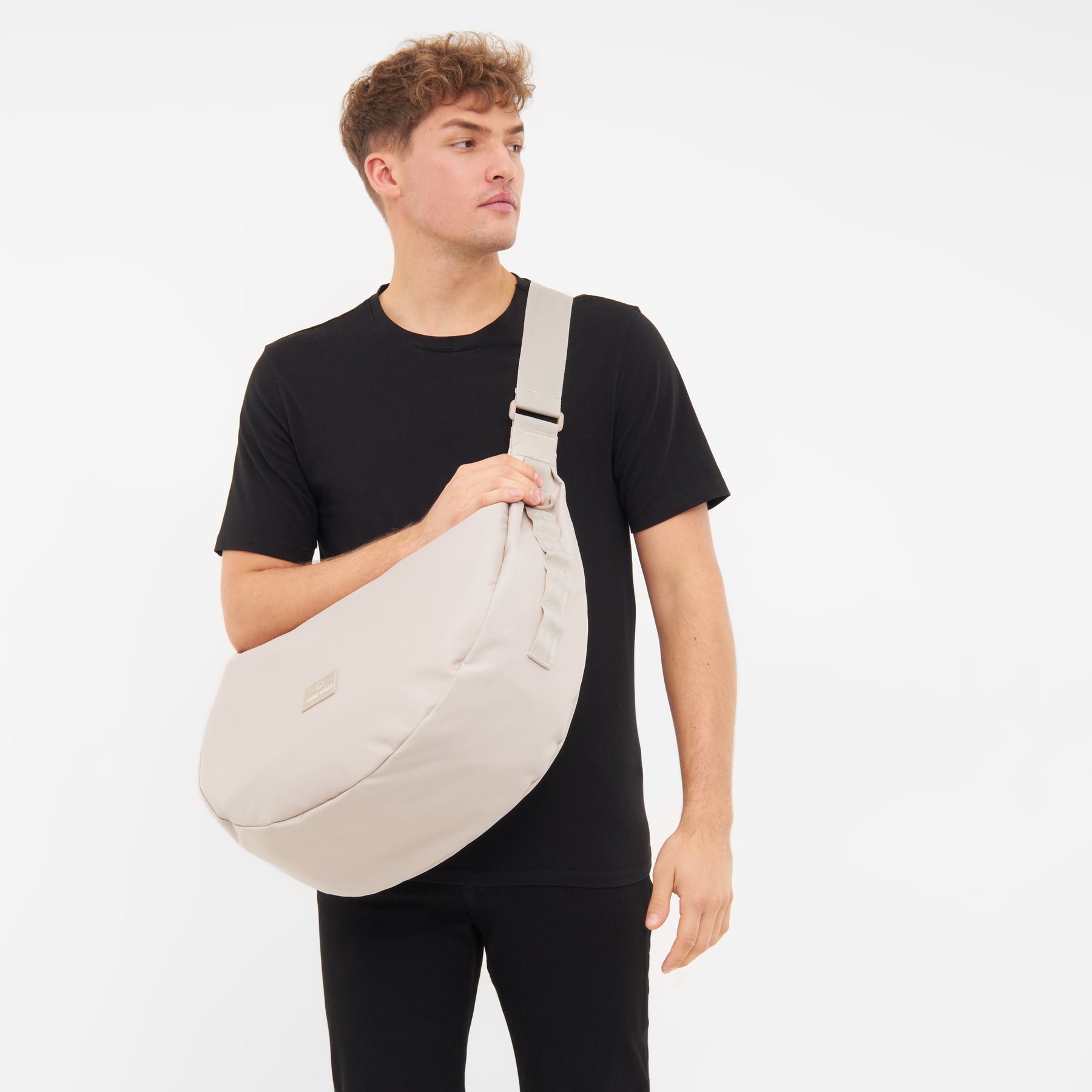 Mann trägt halbmondförmige Tasche 'Ally XL' in Beige quer über den Oberkörper