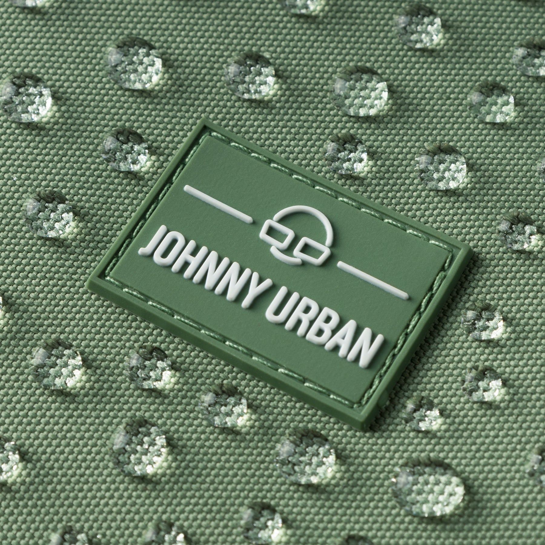 Naheinstellung eines wasserabweisenden grünen Johnny Urban Labels auf Stoff mit Wassertropfen