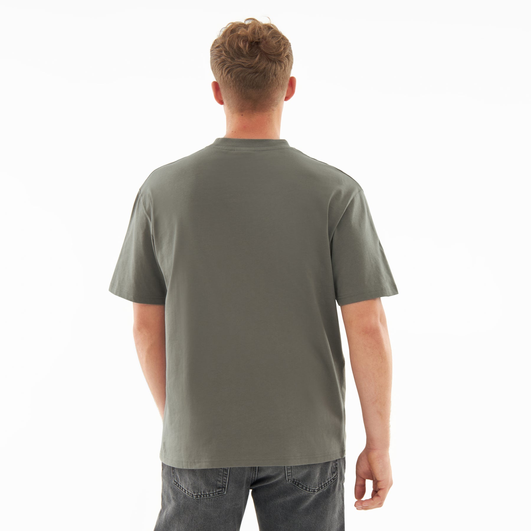 Rückansicht eines Mannes, der ein olivgrünes oversized T-Shirt 'Sammy' und dunkle Jeans trägt