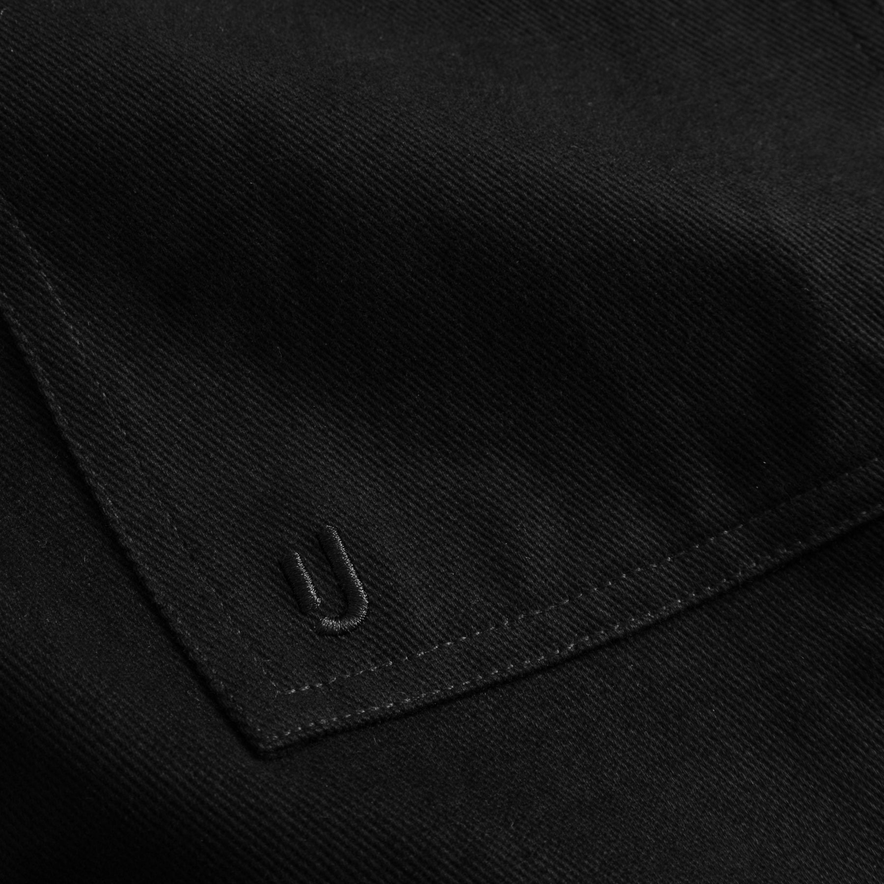 Nahaufnahme des schwarzen Overshirts 'Cameron' aus Baumwolle mit besticktem 'U' Detail