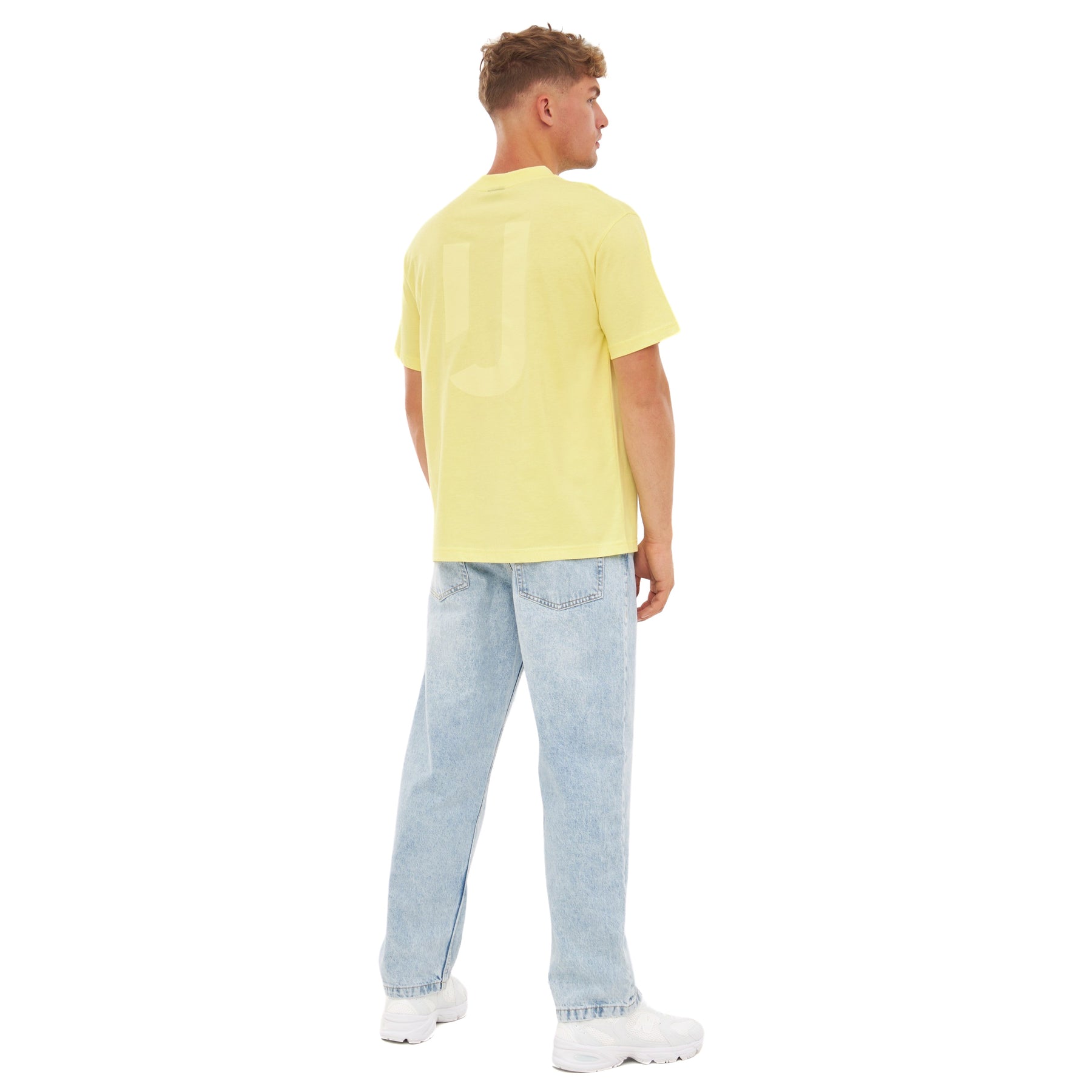 Mann von hinten mit gelbem Oversize-T-Shirt ‚Sammy JU‘ von Johnny Urban, hellblaue Jeans und weißen Schuhen