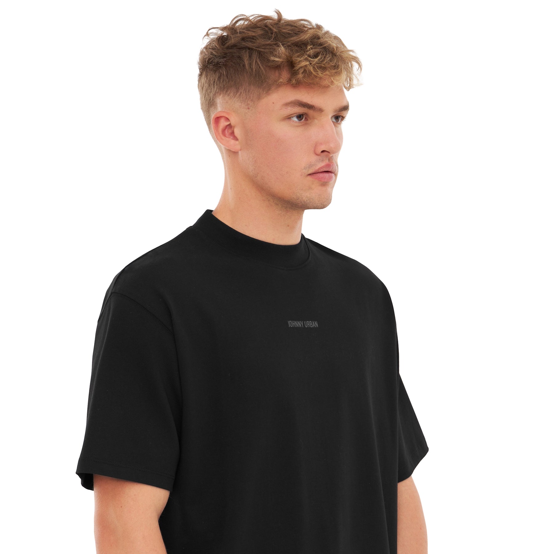 Mann trägt oversized schwarzes T-Shirt 'Sammy Johnny Urban' mit kleinem Schriftzug vorne