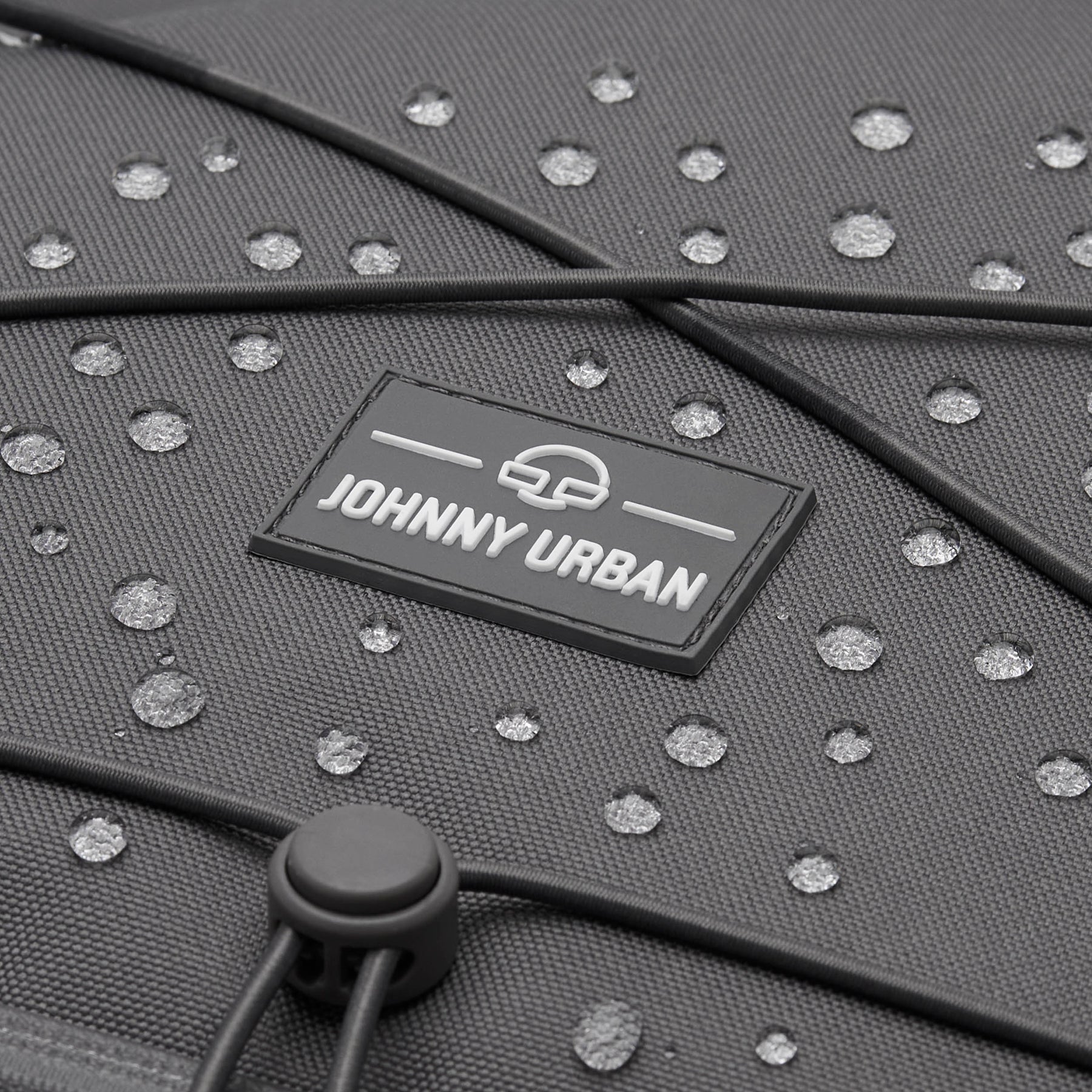 Nahaufnahme des grauen, wasserabweisenden Reiserucksacks 'Allen Large Travel' von Johnny Urban mit Wasserperlen auf der Oberfläche