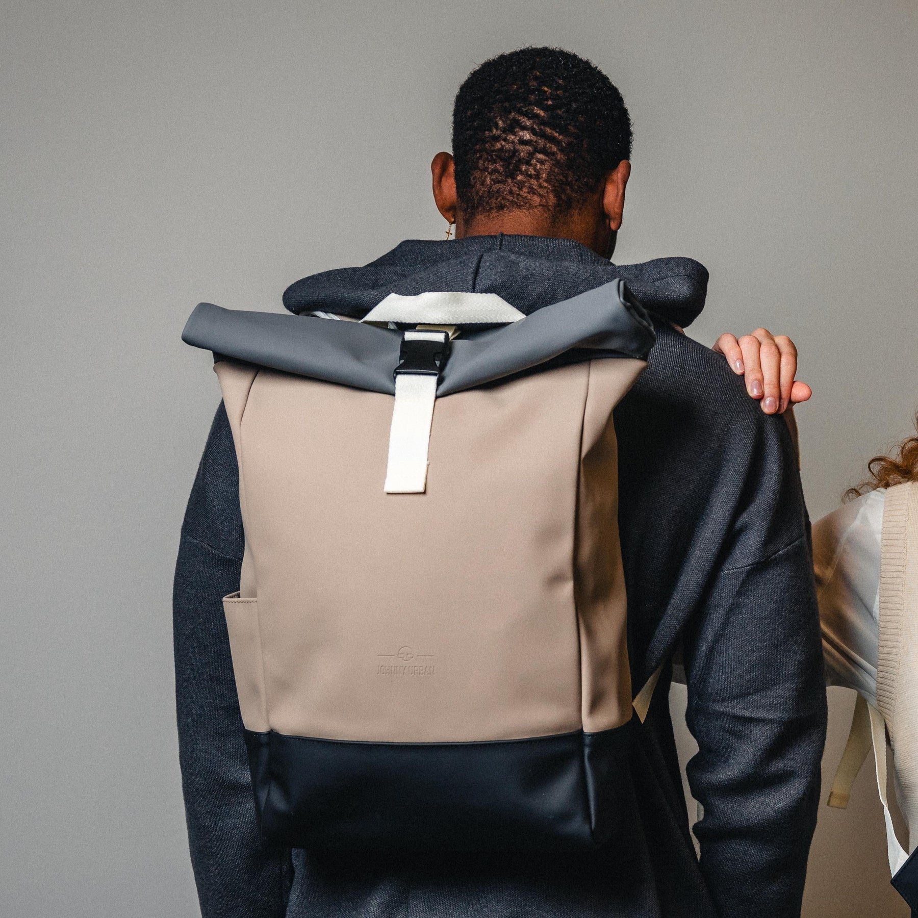 Rolltop Rucksack "Harvey Medium" in Beige mit grauem Verschluss an einem Mann von hinten