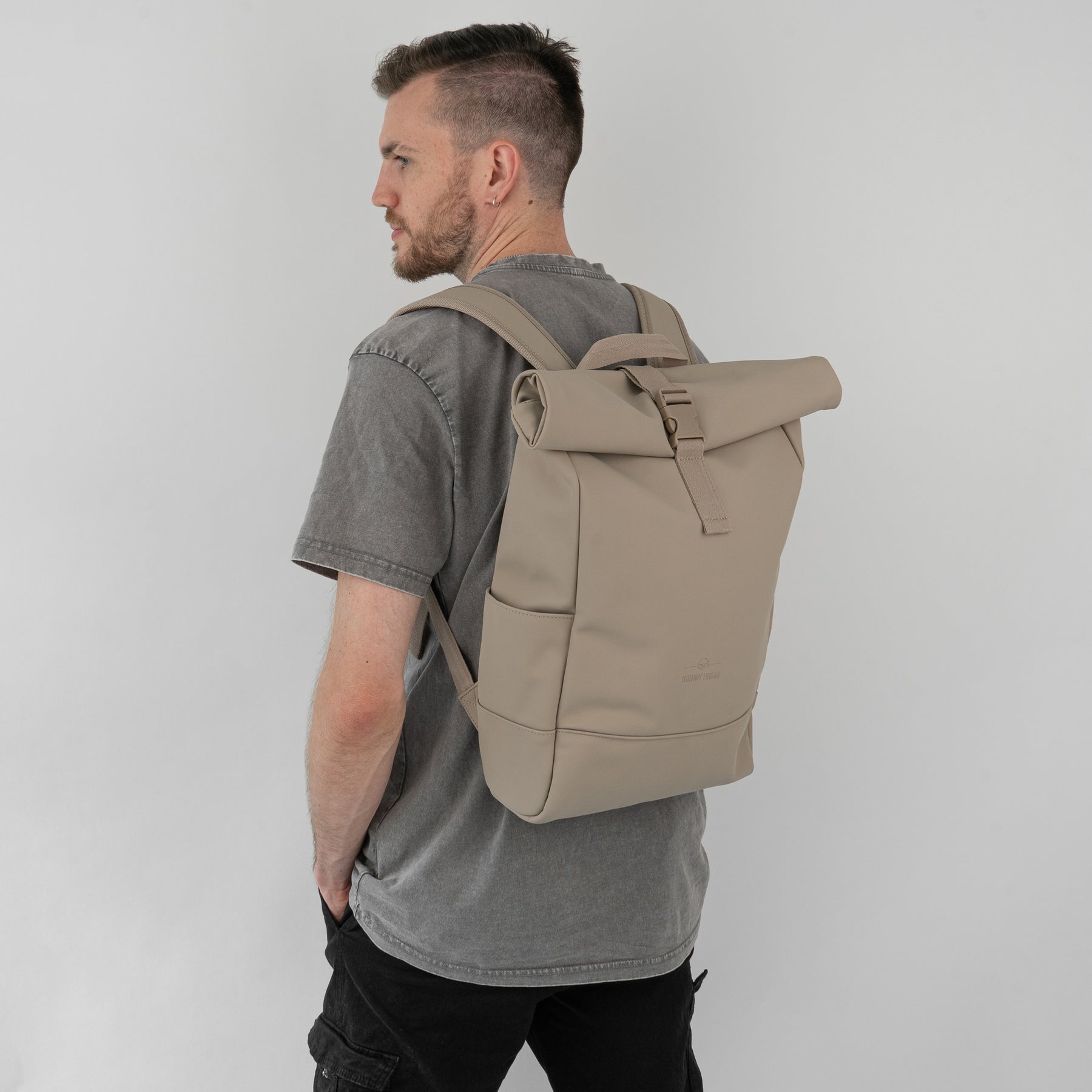 Mann mit grauem T-Shirt und beigem Rolltop Rucksack 'Harvey Medium' von Johnny Urban