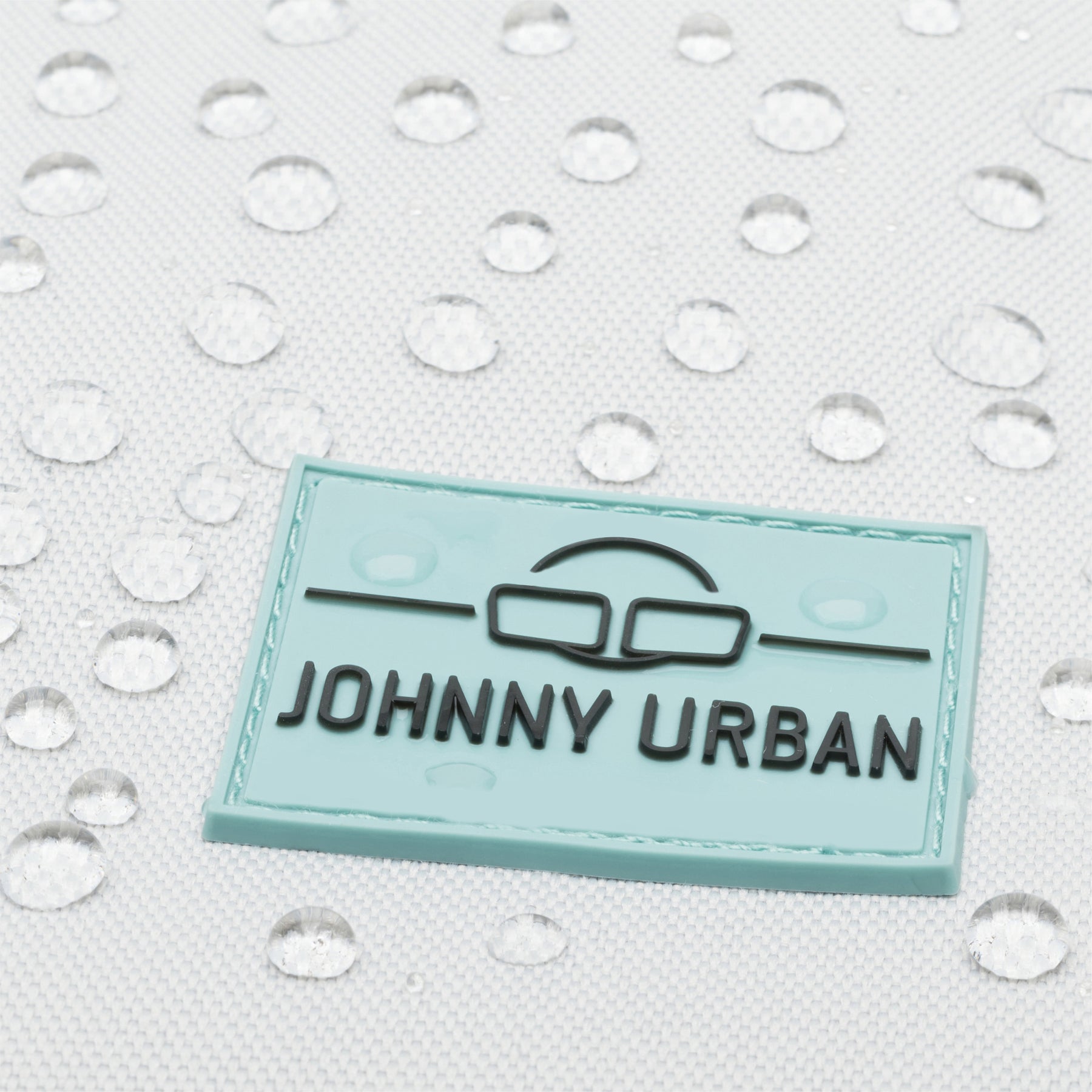 Nahe Aufnahme des Johnny Urban Markenlabels auf einem wasserabweisenden Rolltop-Rucksack